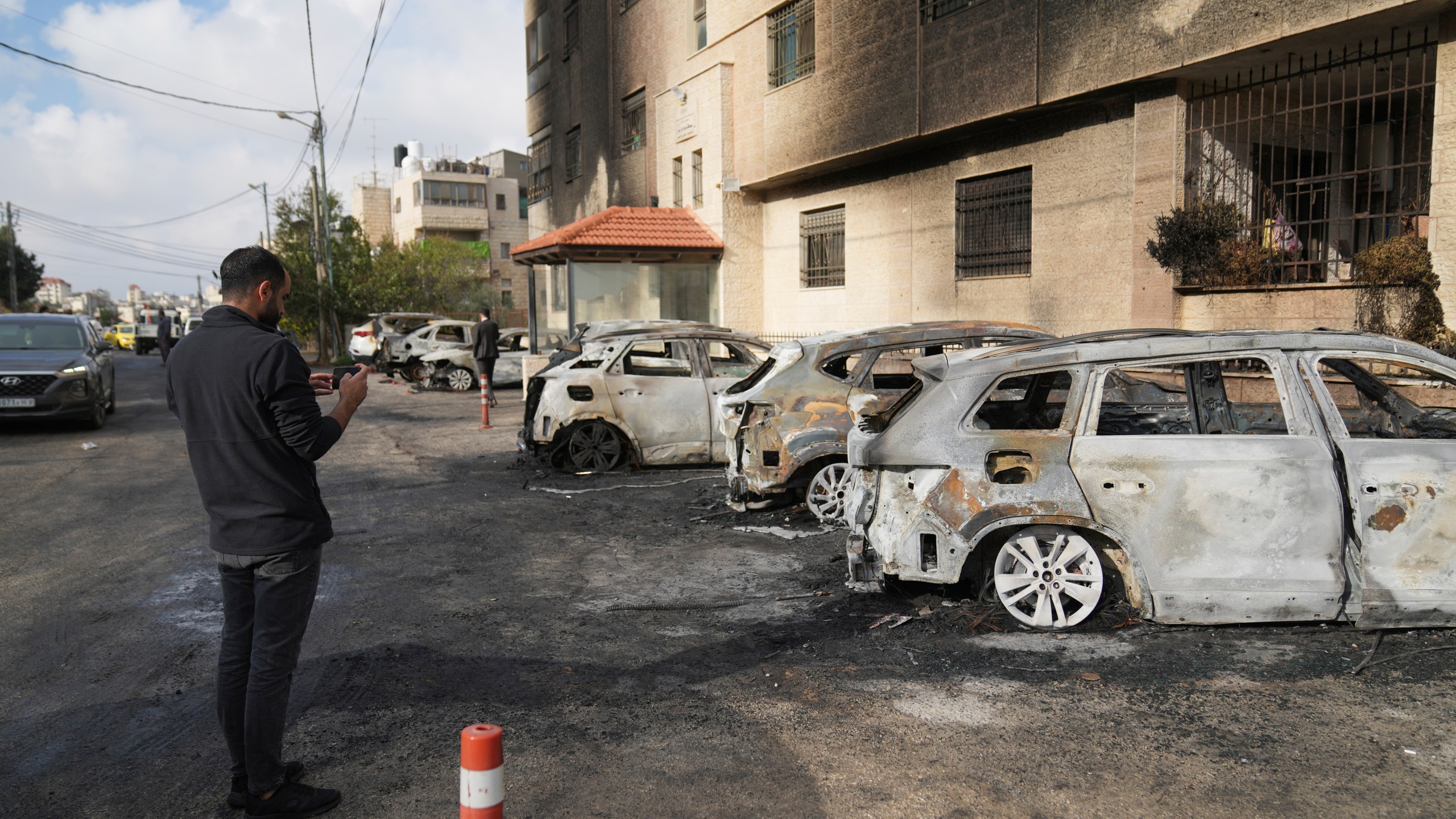 Palestinians inspect vehicles that were burnt during an early morning attack by Israeli settlers, that left at least 18 burnt vehicles, on the outskirts of the West Bank city of al-Bireh Monday, Nov. 4, 2024. (AP Photo/Nasser Nasser)