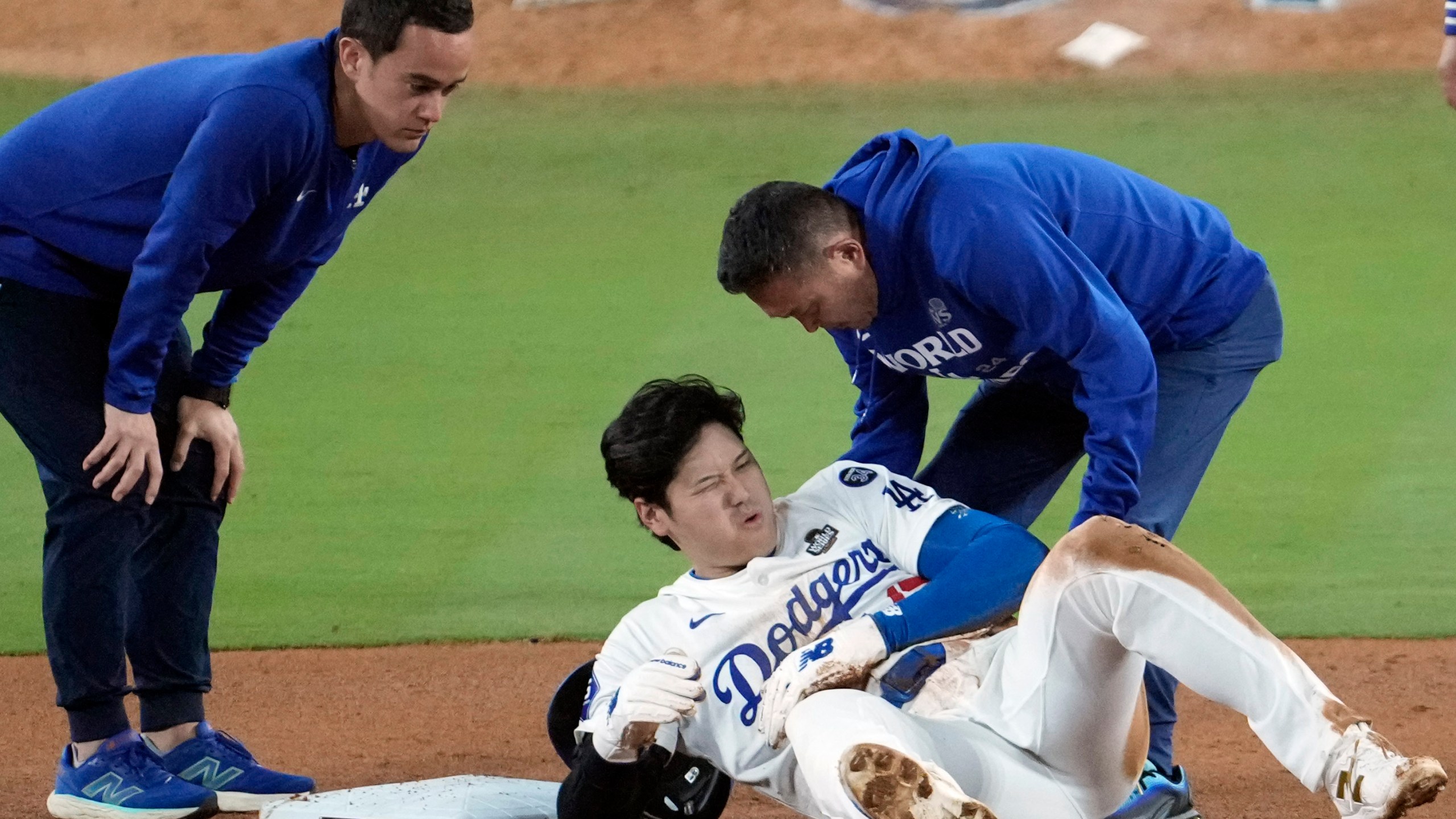 Los Angeles Dodgers' Shohei Ohtani, center, reacts after being injured while trying to steal second base against the New York Yankees during the seventh inning in Game 2 of the baseball World Series, Saturday, Oct. 26, 2024, in Los Angeles. (AP Photo/Julio Cortez)