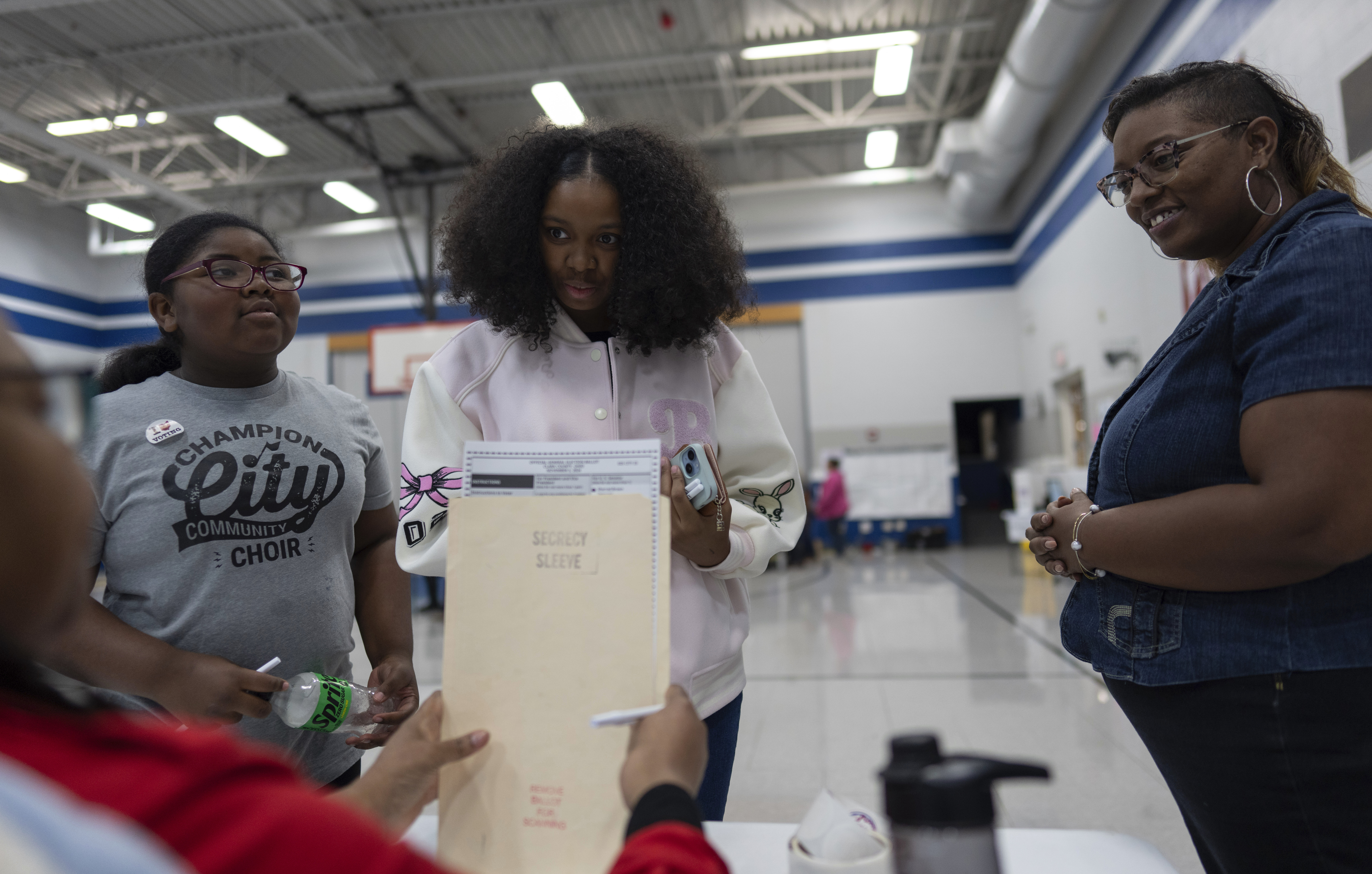 First-time voter Samaira Peterson, center, stands with her mother Khayesha Peterson, right, and her little sister Samaiya Peterson, left, as she prepares to vote at Warder Park-Wayne Elementary School on Election Day, Tuesday, Nov. 5, 2024, in Springfield, Ohio. (AP Photo/Carolyn Kaster)