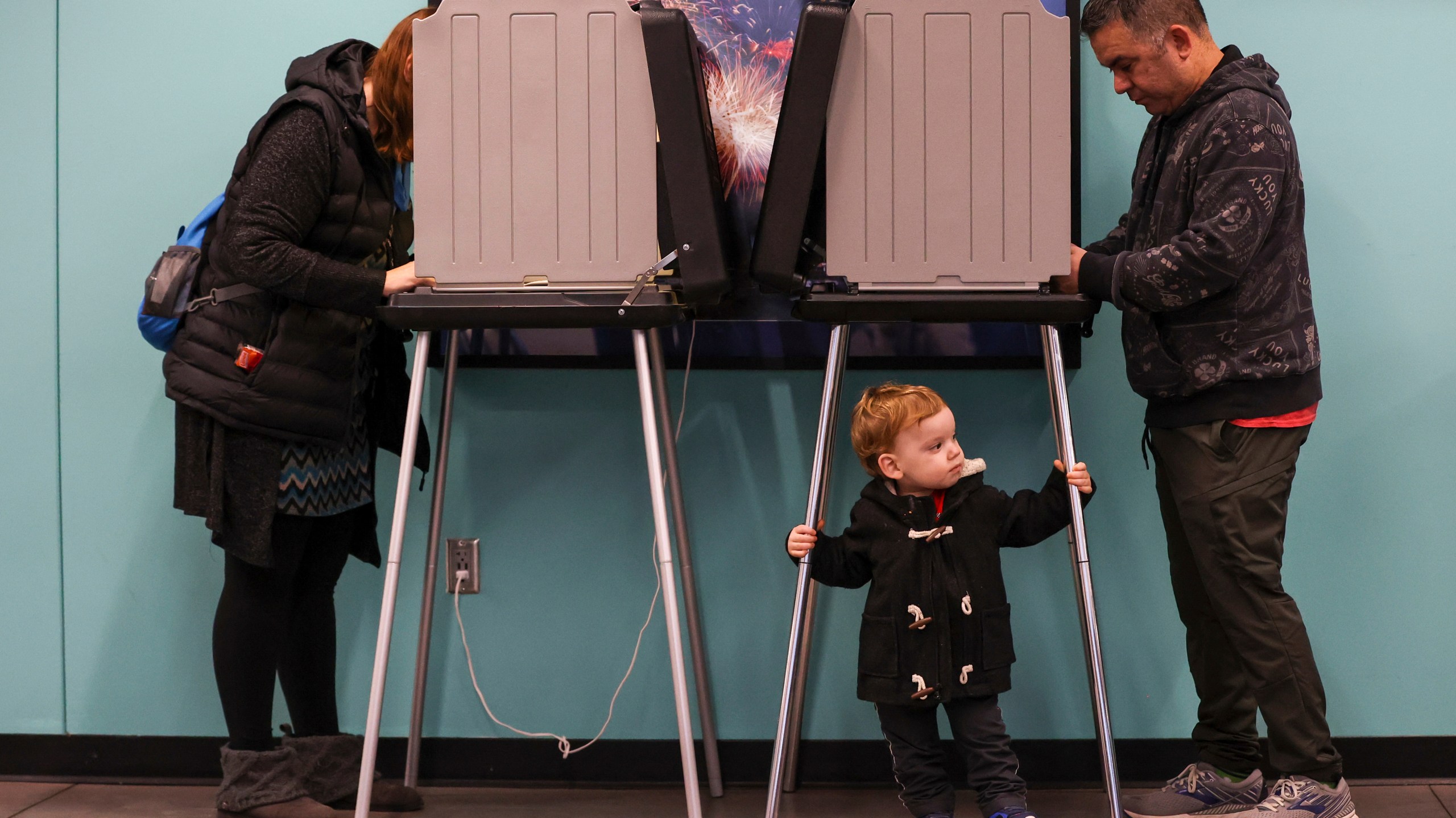 Oliver Barragan, 2, center, waits for his mother, Richelle Barragan, left, as she votes on Election Day at Werner Park, Tuesday, Nov. 5, 2024, in Papillion, Neb. (Liz Rymarev/Omaha World-Herald via AP)