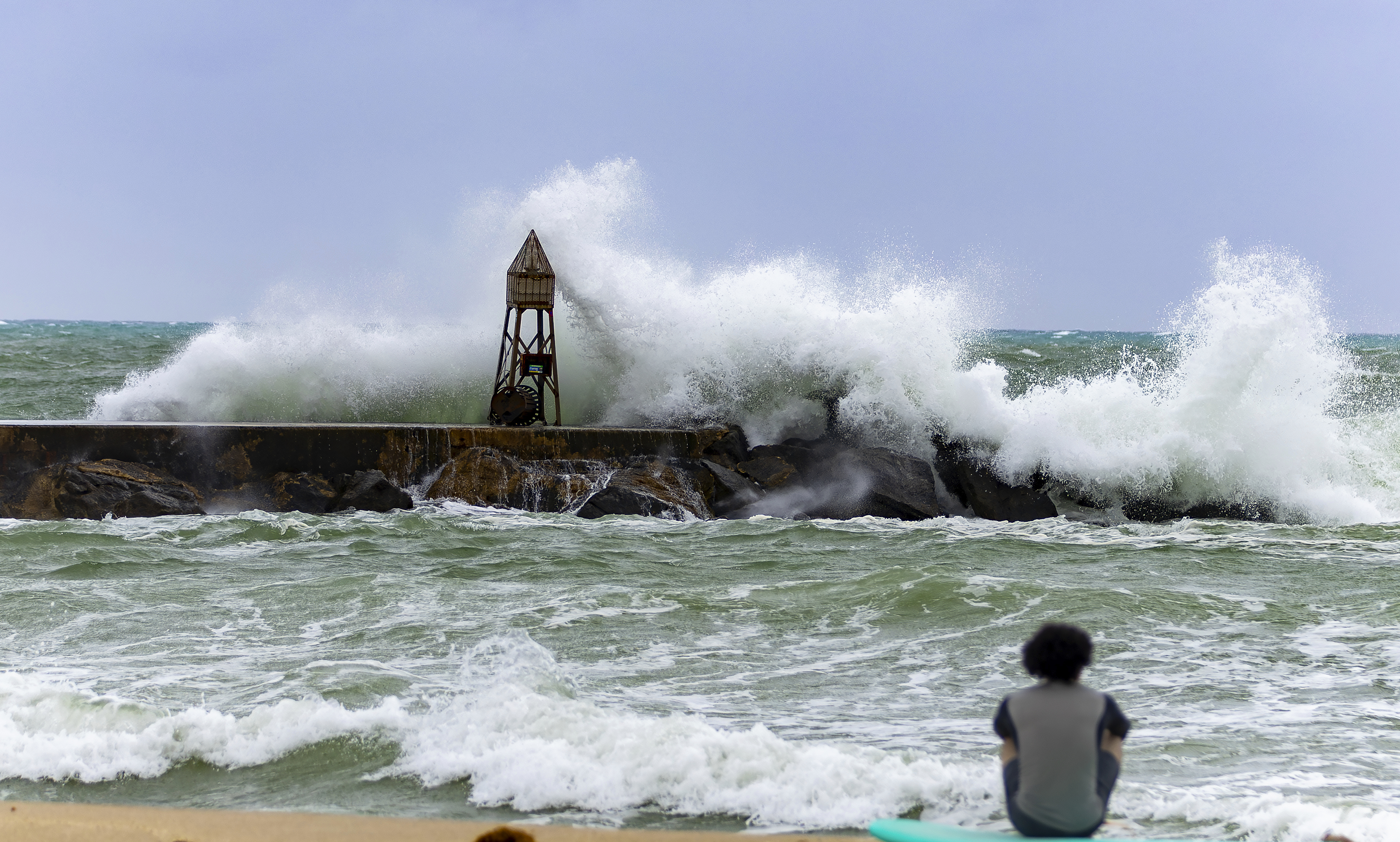 A surfer looks the waves crashing against the jetty at the Bal Harbour Lighthouse on Tuesday, Nov. 5, 2024, in Bal Harbour, Fla. (David Santiago/Miami Herald via AP)