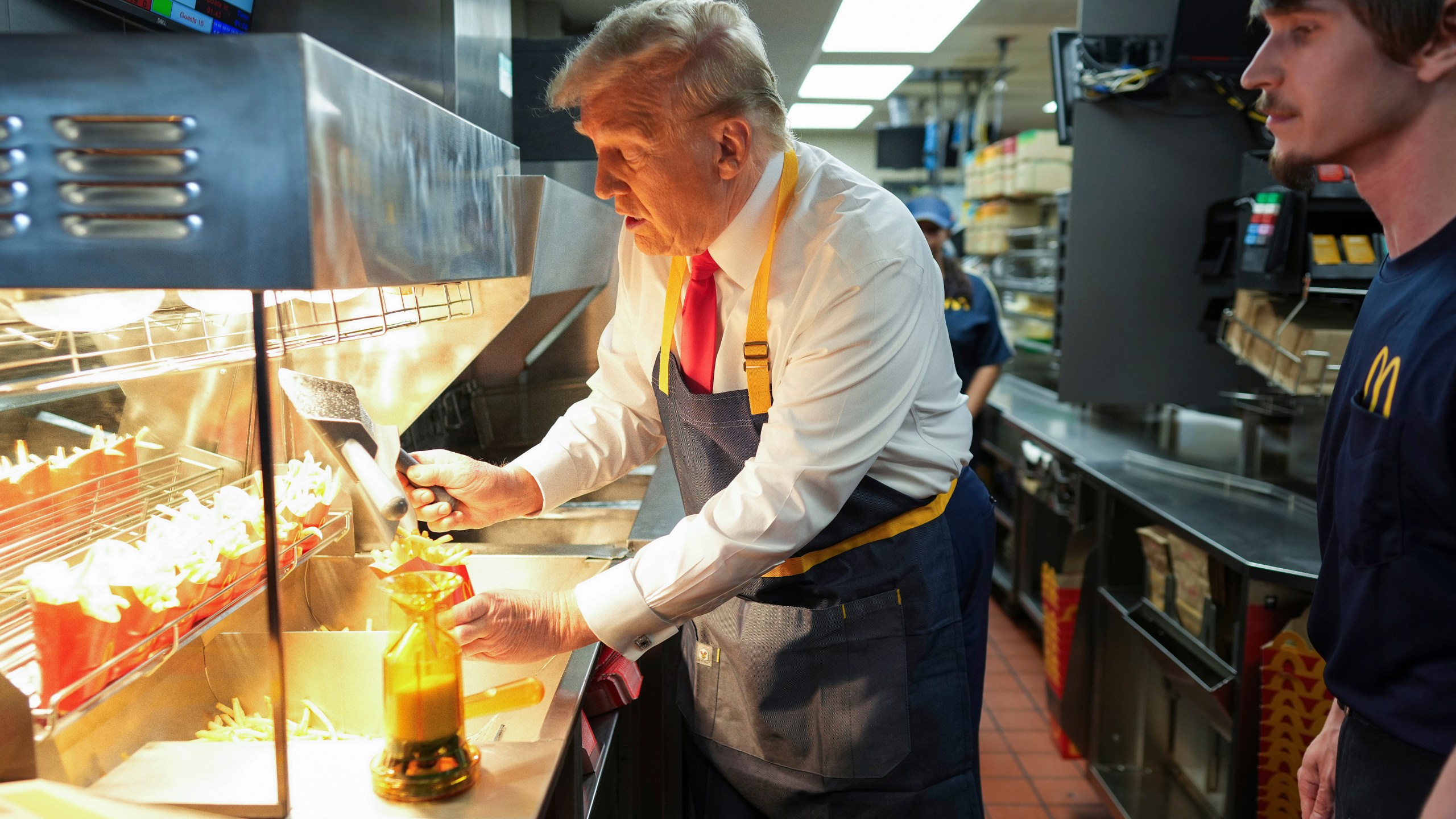 Republican presidential nominee former President Donald Trump serves french fries as an employee looks on during a visit to McDonald's in Feasterville-Trevose, Pa., Sunday, Oct. 20, 2024. (Doug Mills/The New York Times via AP, Pool)