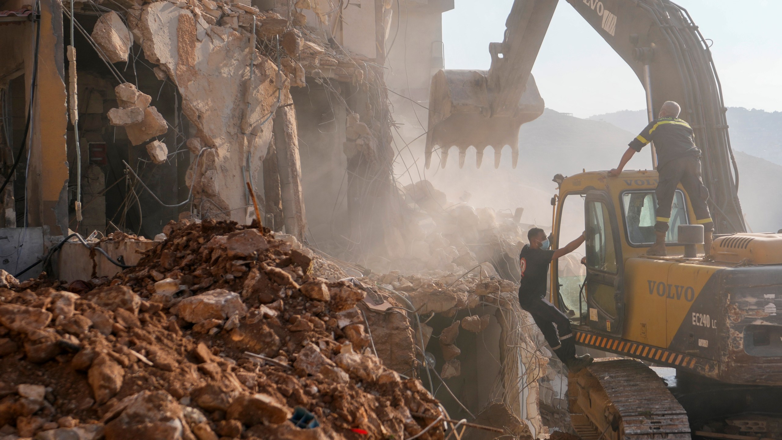 Rescue workers use an excavator to remove the rubble of a destroyed building hit in an Israeli airstrike on Tuesday night, as they search for victims in Barja, Lebanon, Wednesday, Nov. 6, 2024. (AP Photo/Hassan Ammar)