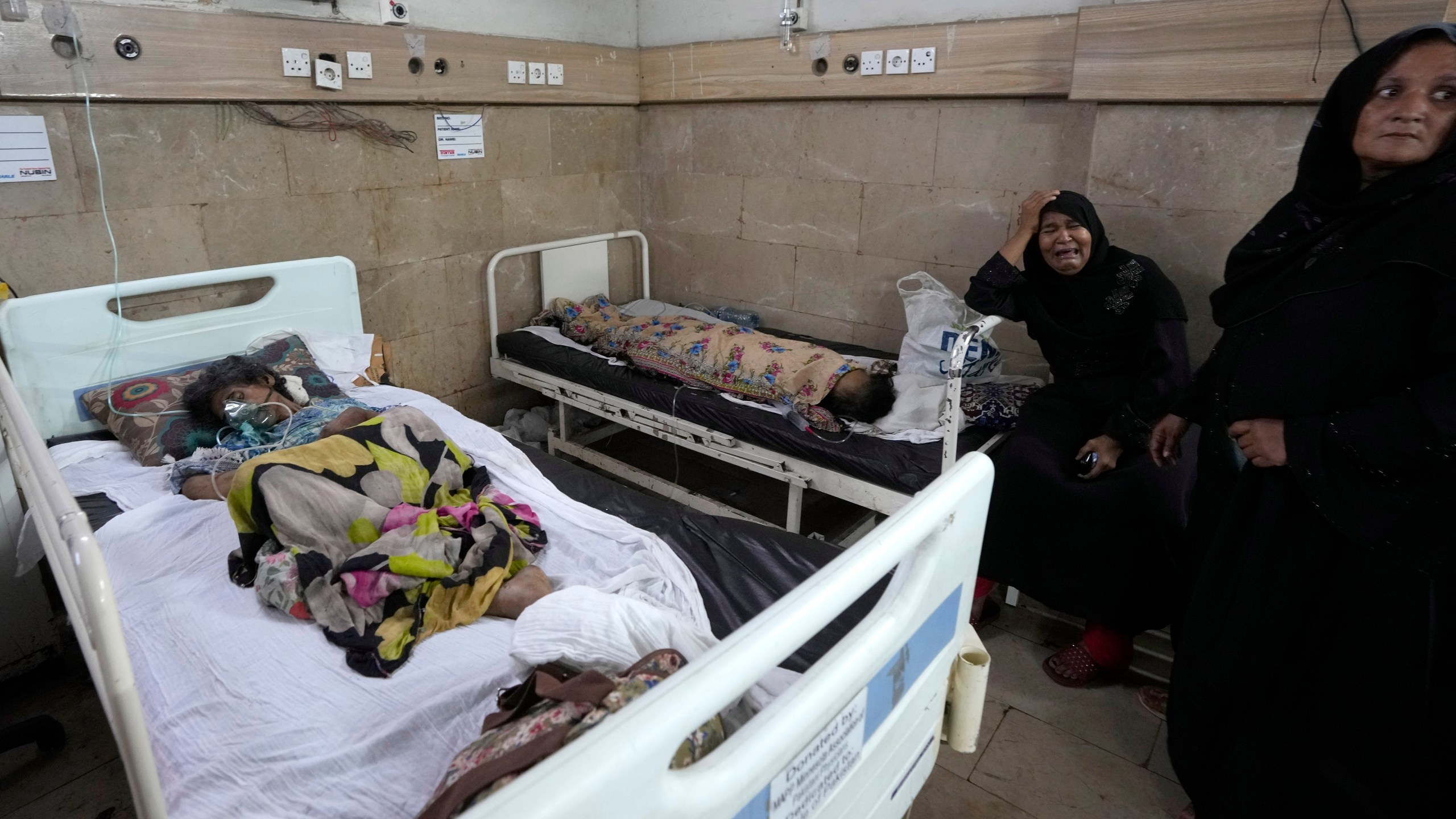 FILE - A woman, center, weeps as patients of heatstroke receive treatment at a hospital in Karachi, Pakistan, June 25, 2024. (AP Photo/Fareed Khan, File)