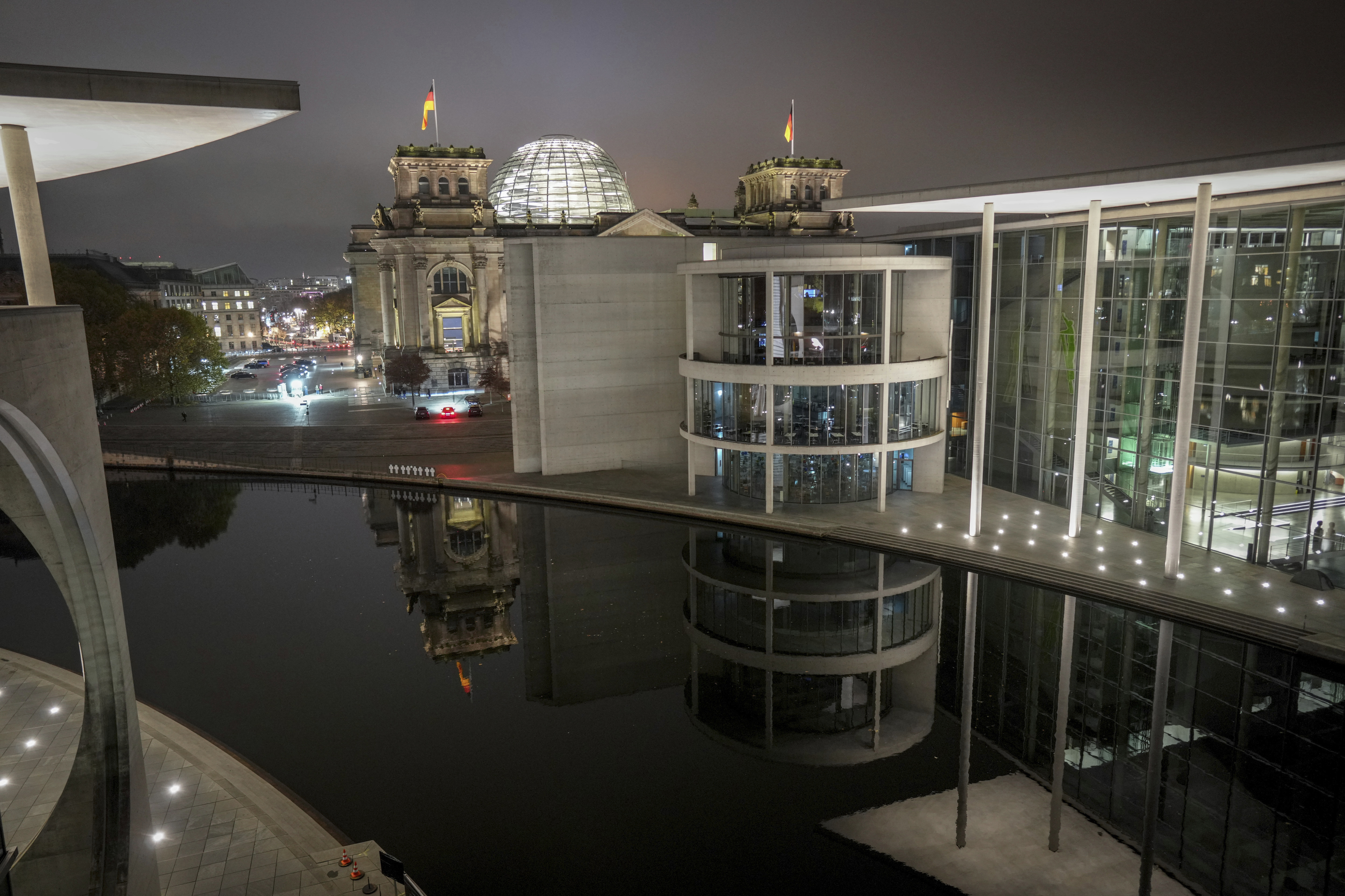 Parts of the Reichstag building with the Bundestag and the Paul Löbe House in Berlin's government district are reflected in the Spree at night, early Thursday, Nov. 7, 2024. (Kay Nietfeld/dpa via AP)