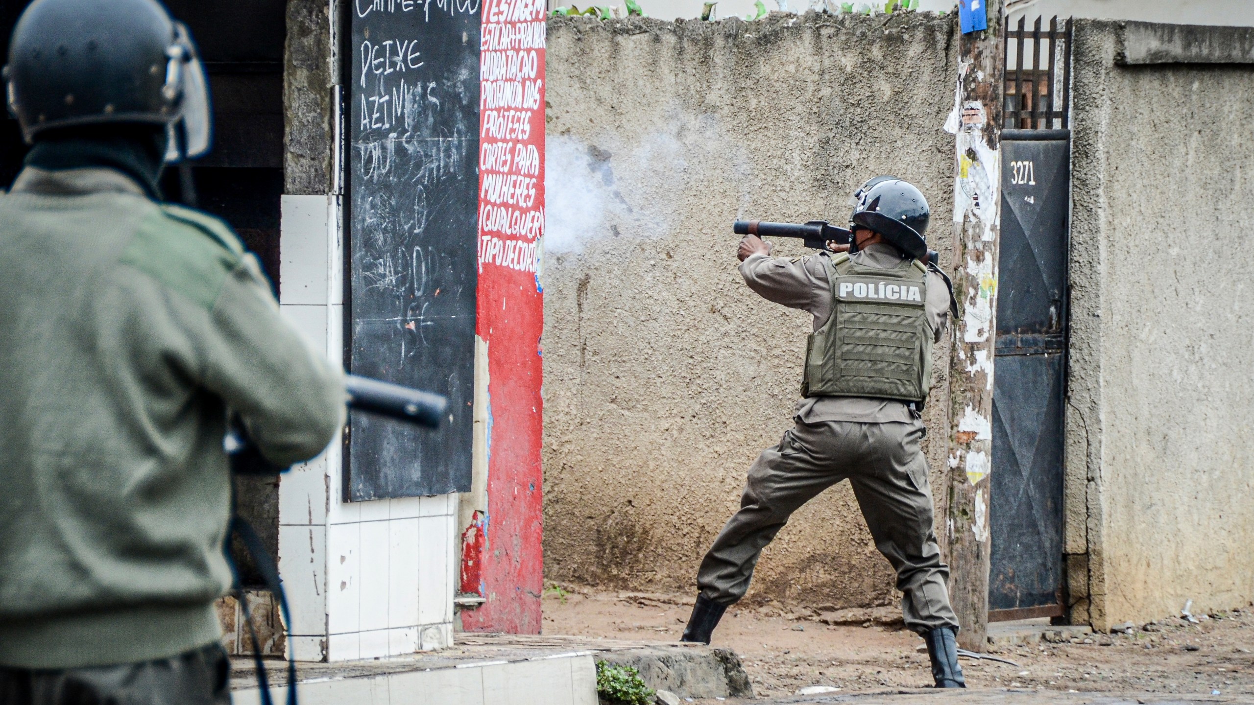 A police officer aims his weapon at protesters in Maputo, Mozambique, Thursday, Nov. 7, 2024. Protesters dispute the outcome of the Oct. 9 elections that saw the ruling Frelimo party extend its 49-year rule. (AP Photo/Carlos Uqueio)