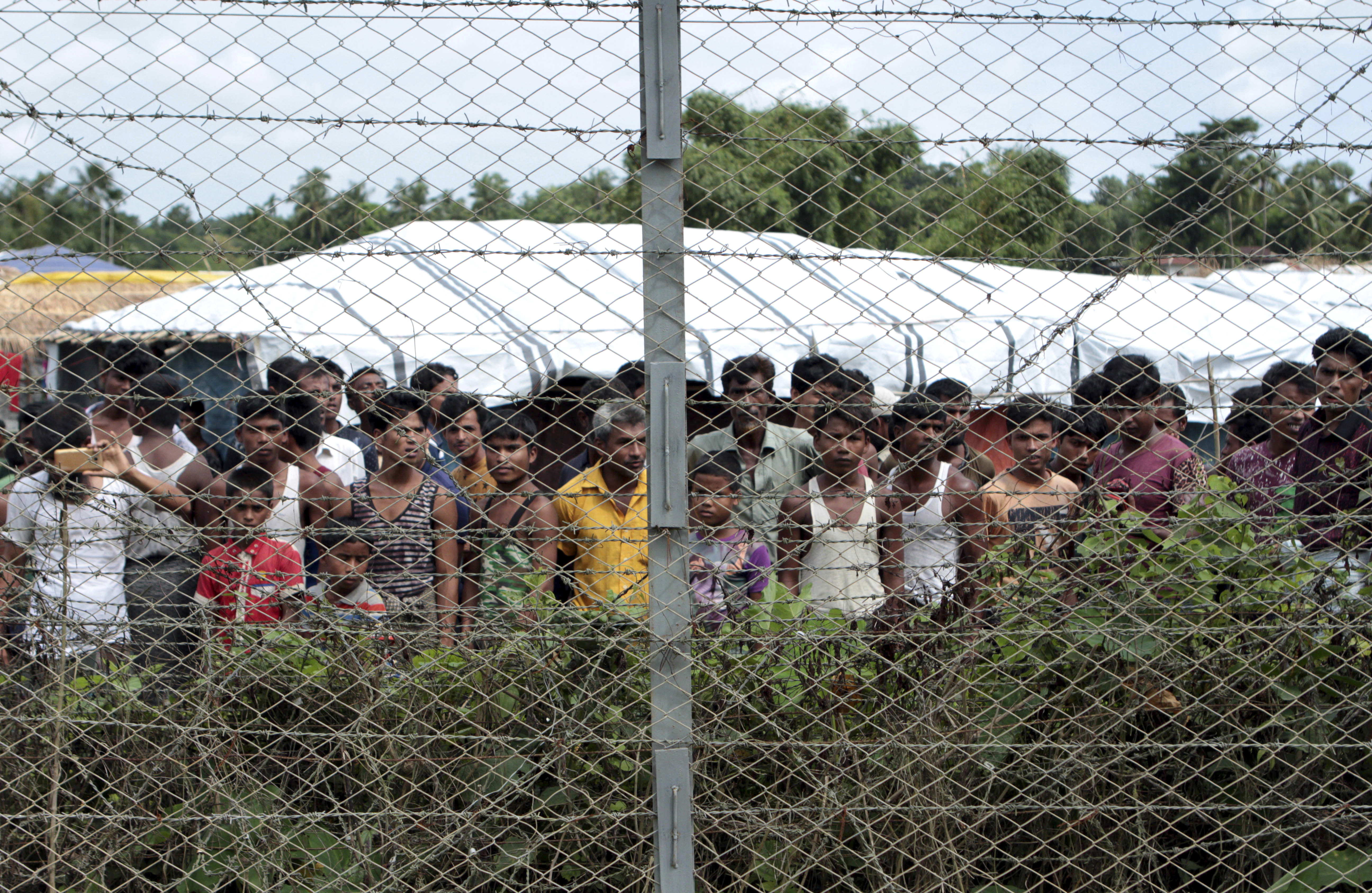 FILE - Rohingya refugees gather near a fence during a government organized media tour, to a no-man's land between Myanmar and Bangladesh, near Taungpyolatyar village, Maung Daw, northern Rakhine State, Myanmar, June 29, 2018. (AP Photo/Min Kyi Thein, File)