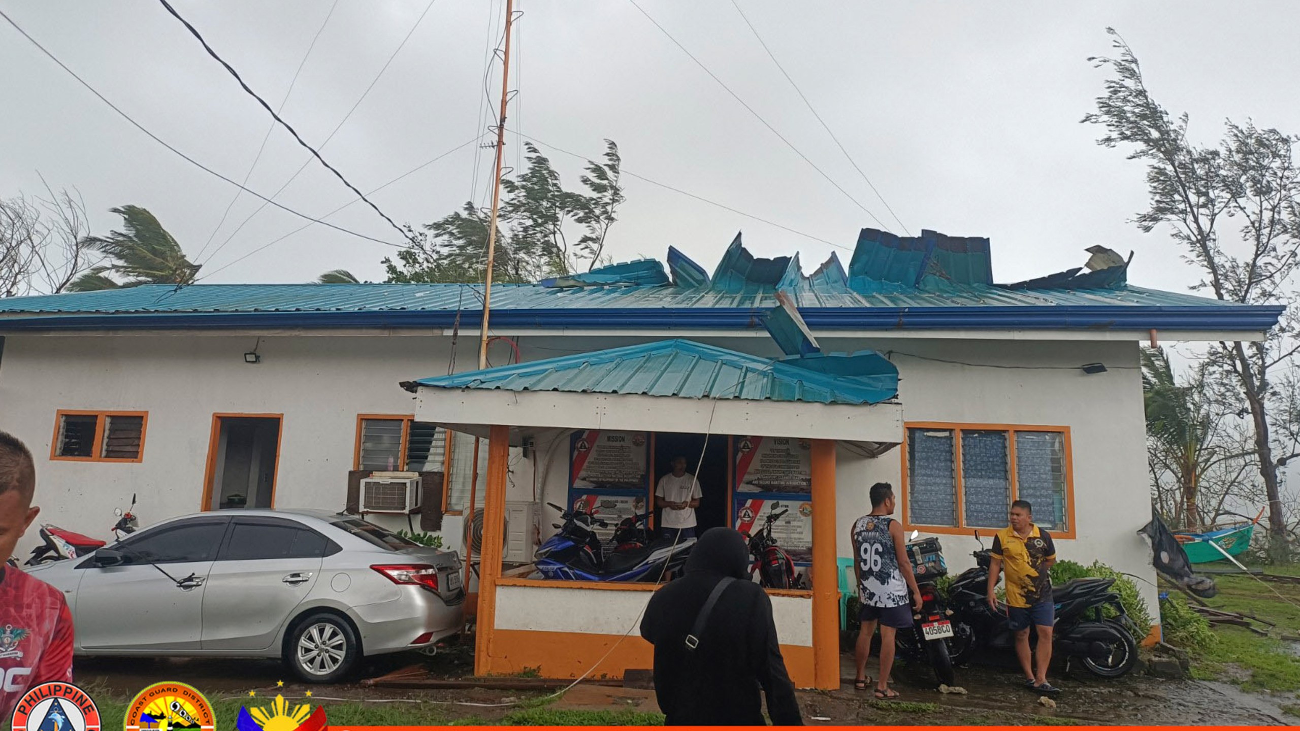 In this photo provided by Philippine Coast Guard, its members stand outside their damaged building due to Typhoon Yinxing in Santa Ana, Cagayan province, northern Philippines Thursday Nov. 7, 2024. (Philippine Coast Guard via AP)