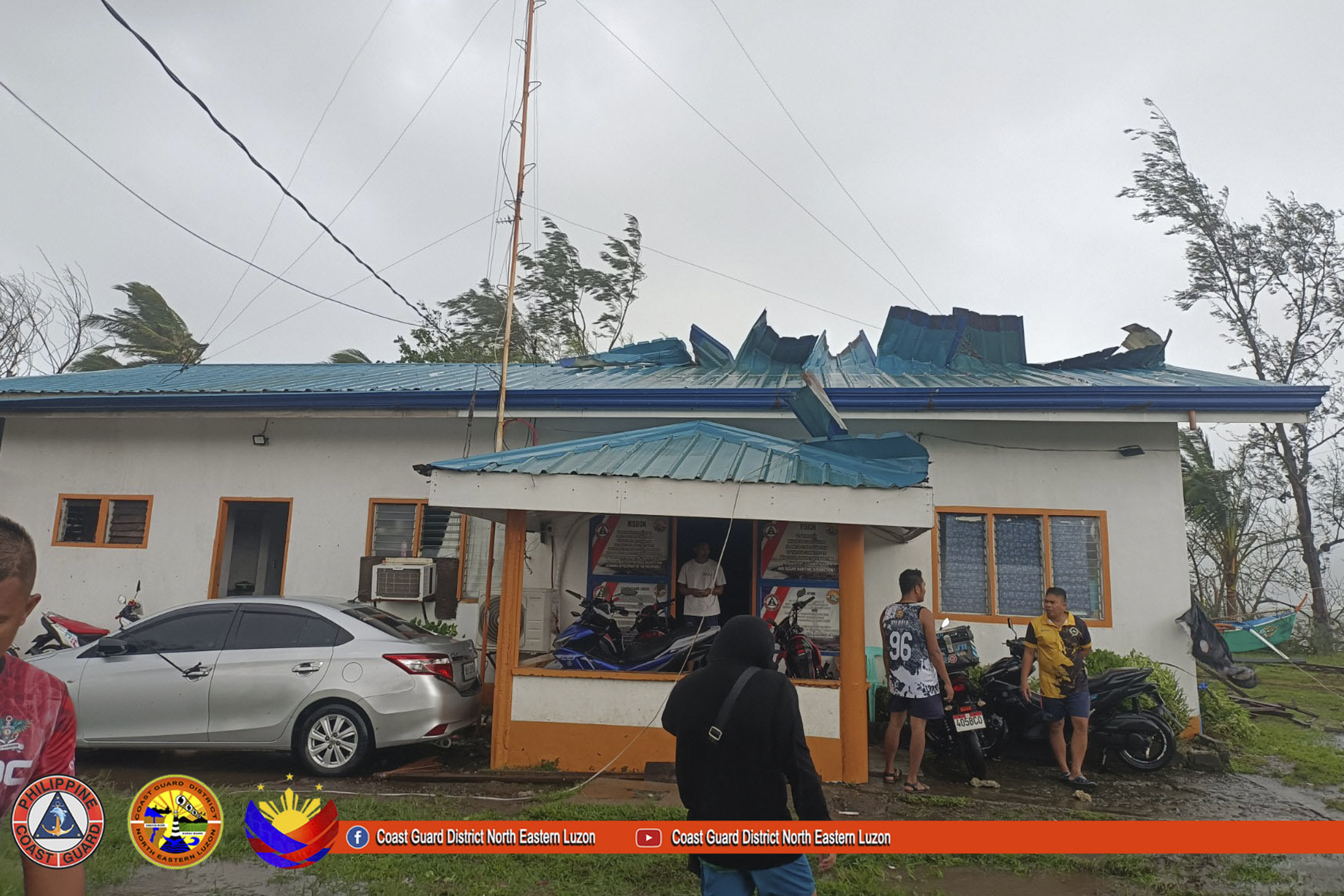 In this photo provided by Philippine Coast Guard, its members stand outside their damaged building due to Typhoon Yinxing in Santa Ana, Cagayan province, northern Philippines Thursday Nov. 7, 2024. (Philippine Coast Guard via AP)