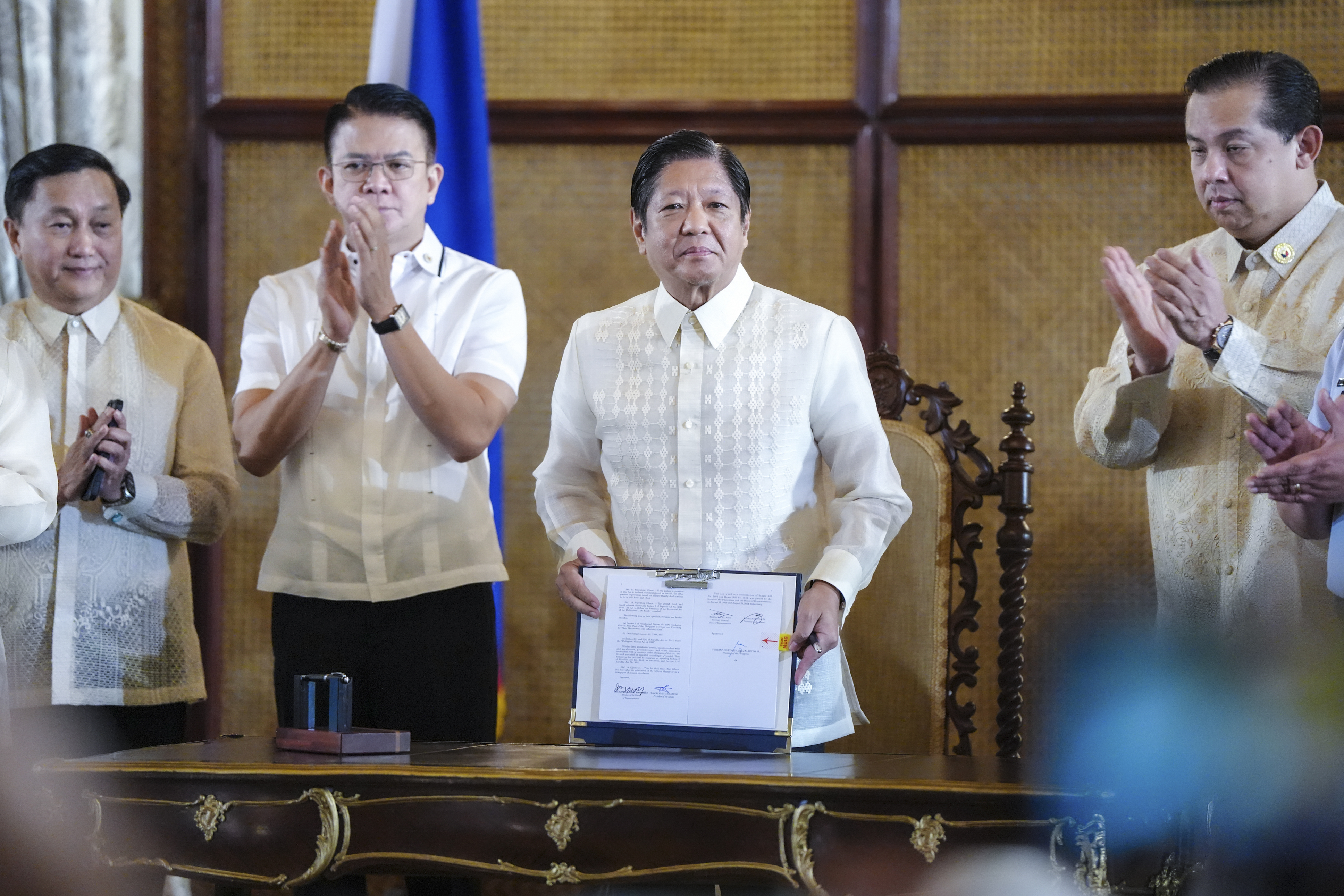 In this photo provided by the Malacanang Presidential Communications Office, Philippine President Ferdinand Marcos Jr., second from right, shows a document beside Senate President Francis Escudero, second from left, and House Speaker Martin Romualdez during the ceremonial signing of the Philippine Maritime Zones and Philippine Archipelagic Sea Lanes Act at the Malacanang presidential palace in Manila, Philippines on Friday, Nov. 8, 2024. (Malacanang Presidential Communications Office via AP)