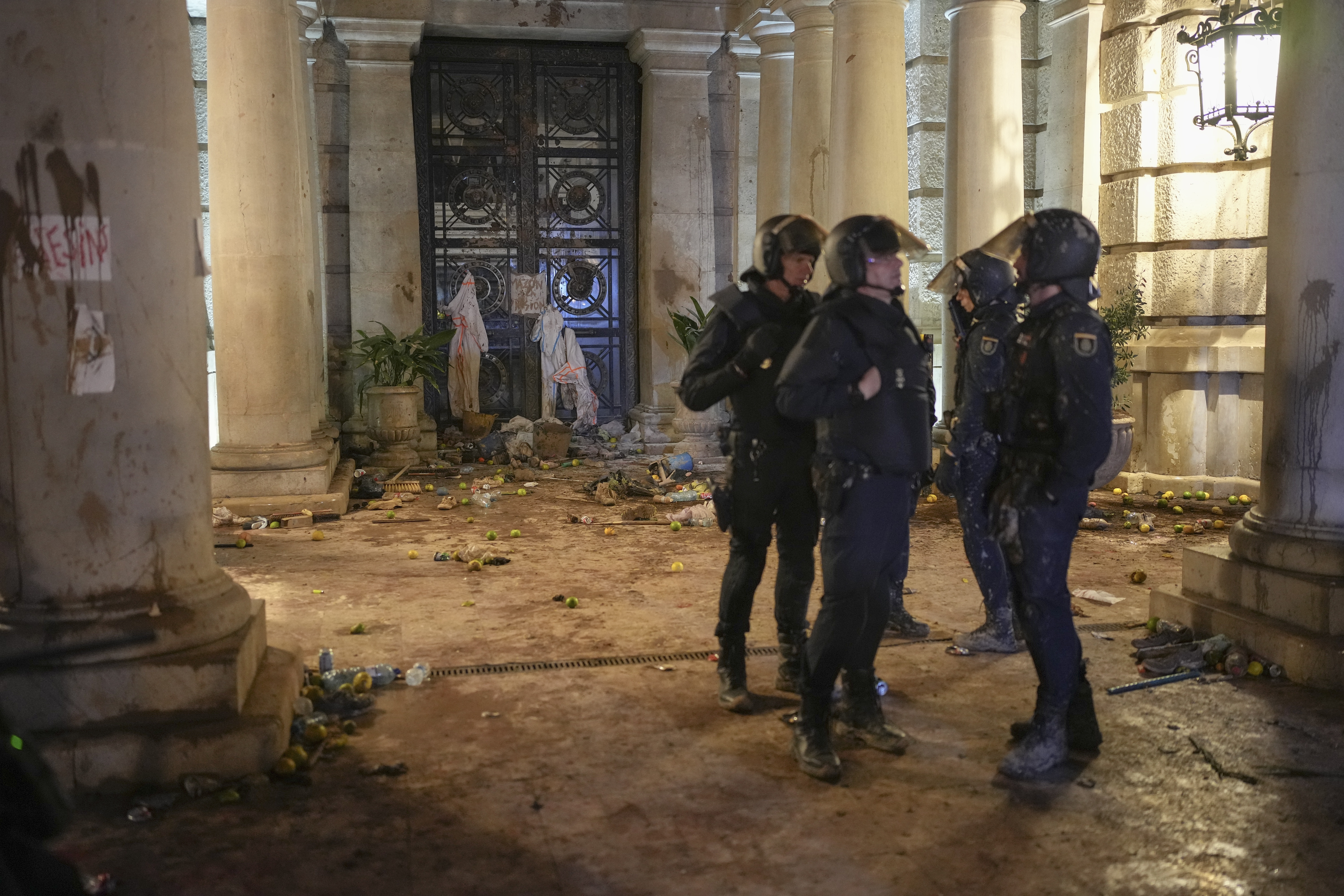 Riot police stand next to a government building littered by some demonstrators during minor clashes after a peaceful protest organized by social and civic groups, denouncing the handling of recent flooding under the slogan "Mazon, Resign," aimed at the president of the regional government Carlos Mazon, in Valencia, Spain, Saturday, Nov. 9, 2024. (AP Photo/Emilio Morenatti)