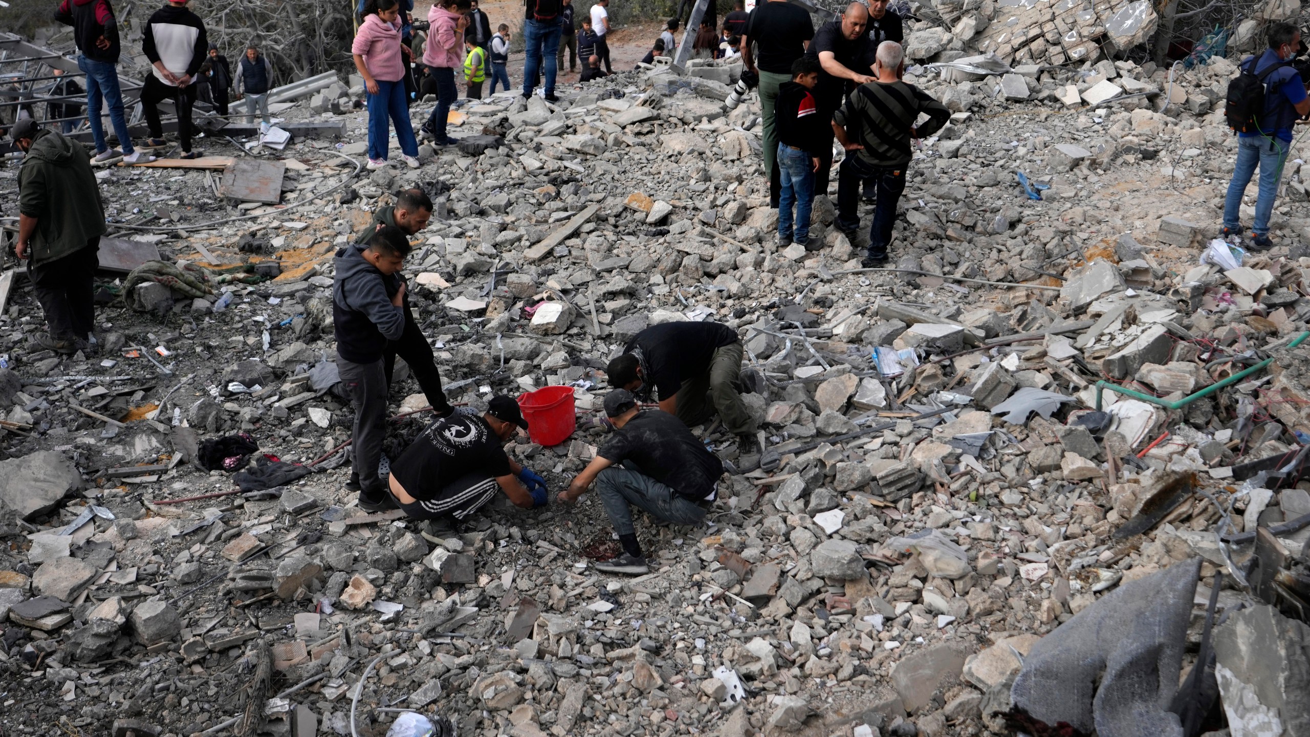 Rescue workers and people, centre, search for victims under the rubble of a destroyed house hit in an Israeli airstrike, in Aalmat village, northern Lebanon, Sunday, Nov. 10, 2024. (AP Photo/Hassan Ammar)