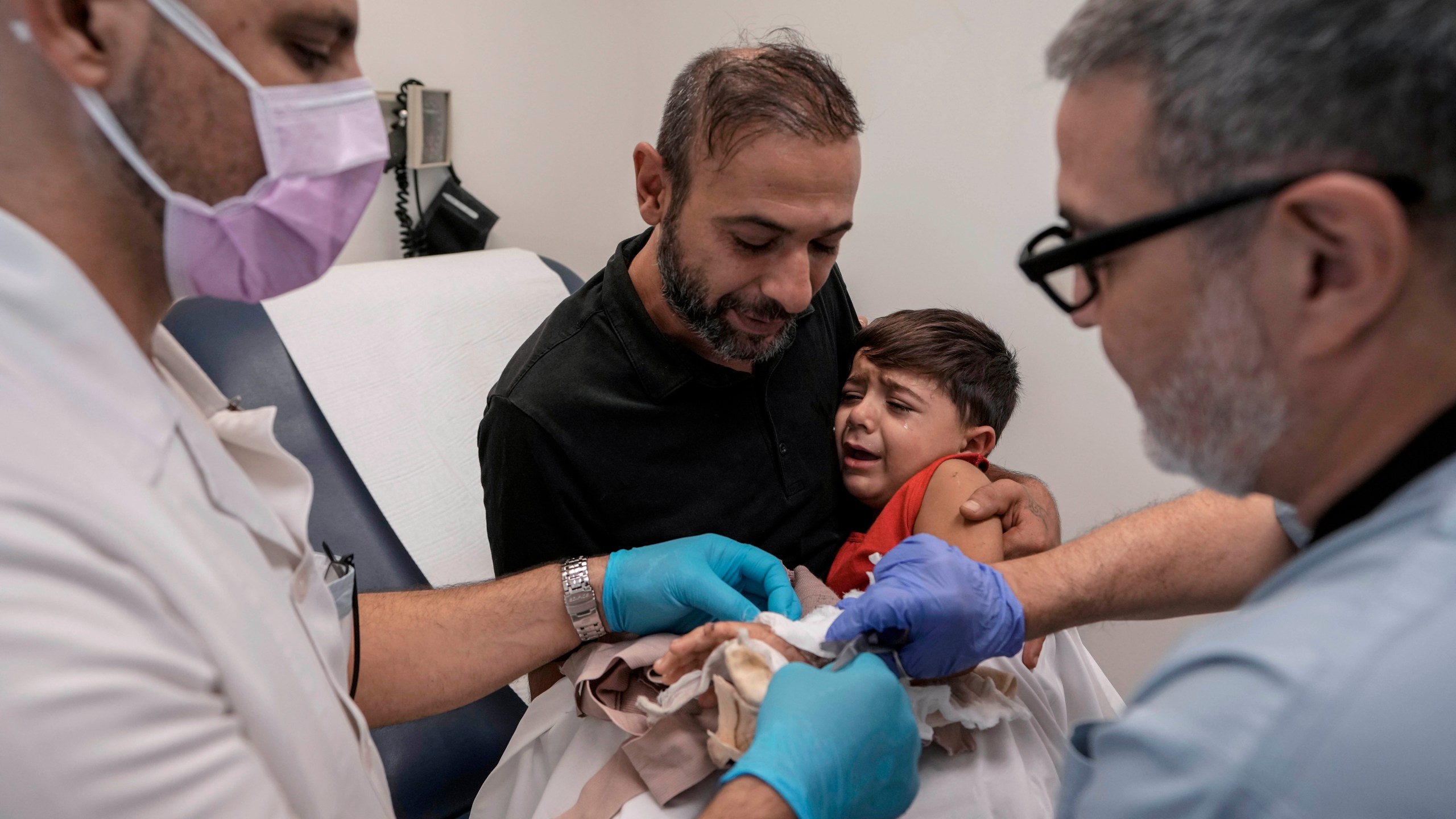 Hassan Mikdad, holds his son Hussein Mikdad, 4, who was injured on Oct. 2 in an Israeli airstrike at a densely-populated neighborhood south of Beirut, during a check up by his doctor at the American University of Beirut Medical Center (AUBMC), in Beirut, Lebanon, Tuesday, Nov. 5, 2024. (AP Photo/Bilal Hussein)