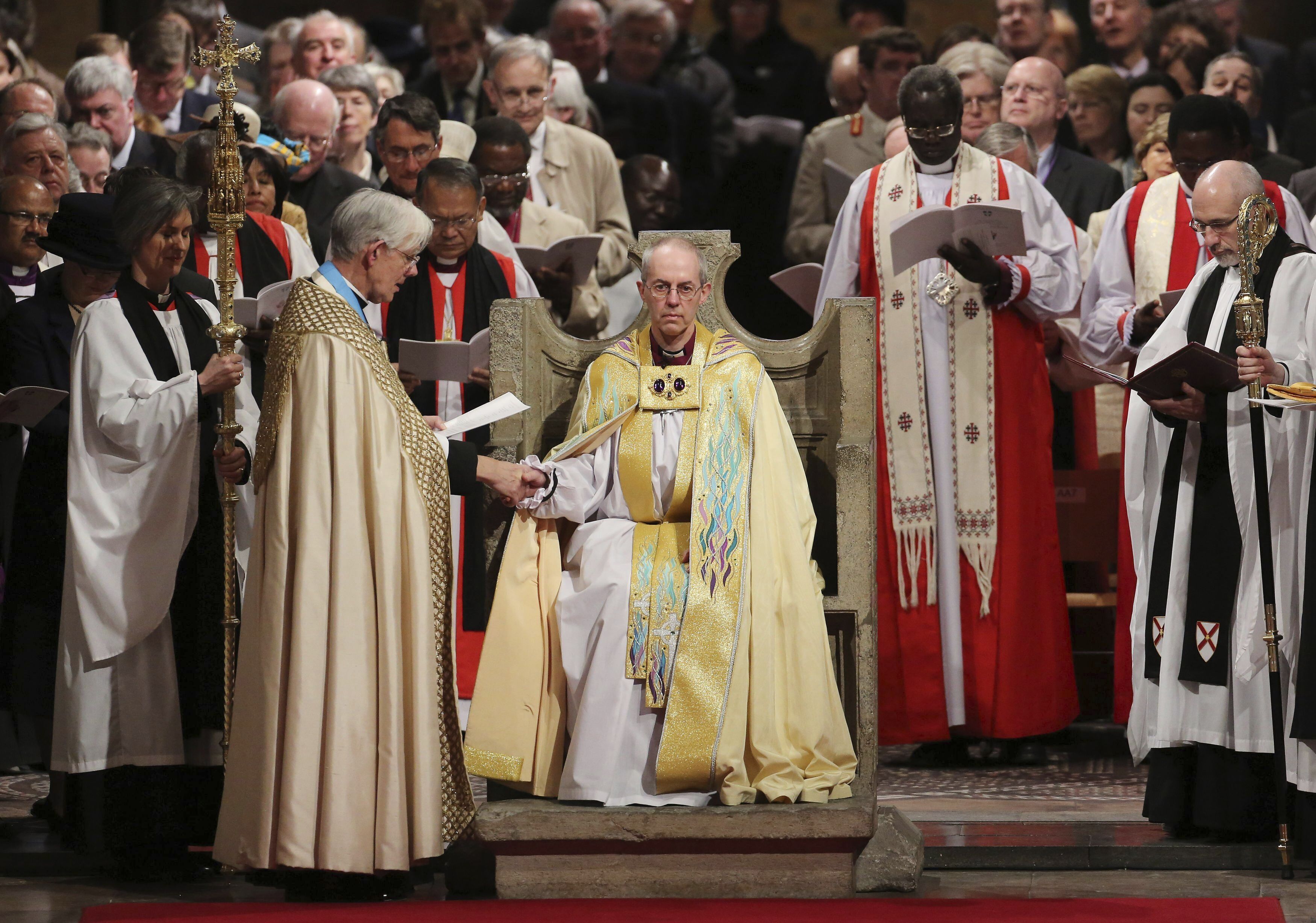 FILE - The Most Reverend Justin Welby sits in the Chair of St Augistine as the Dean of Canterbury Robert Willis takes him by the hand during his enthronement service to become Archbishop of Canterbury at Canterbury Cathedral in Canterbury, England, Thursday, March 21, 2013. (Gareth Fuller, Pool Photo via AP, File)