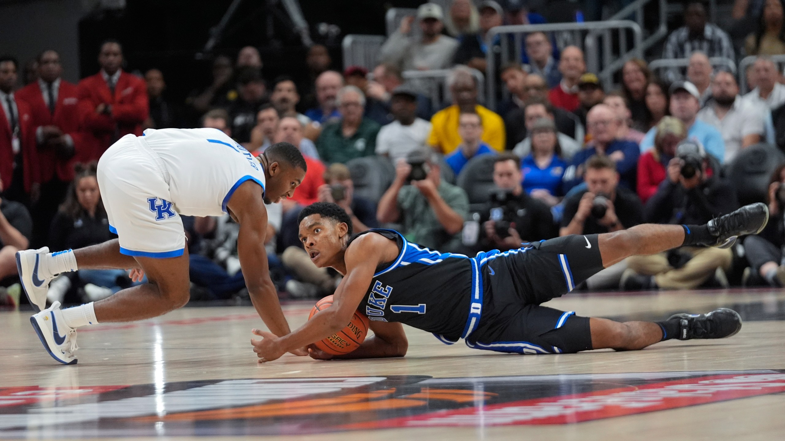 Duke guard Caleb Foster (1) and Kentucky guard Lamont Butler (1) dive for a loose ball during the first half of an NCAA college basketball game, Tuesday, Nov. 12, 2024, in Atlanta. (AP Photo/John Bazemore )