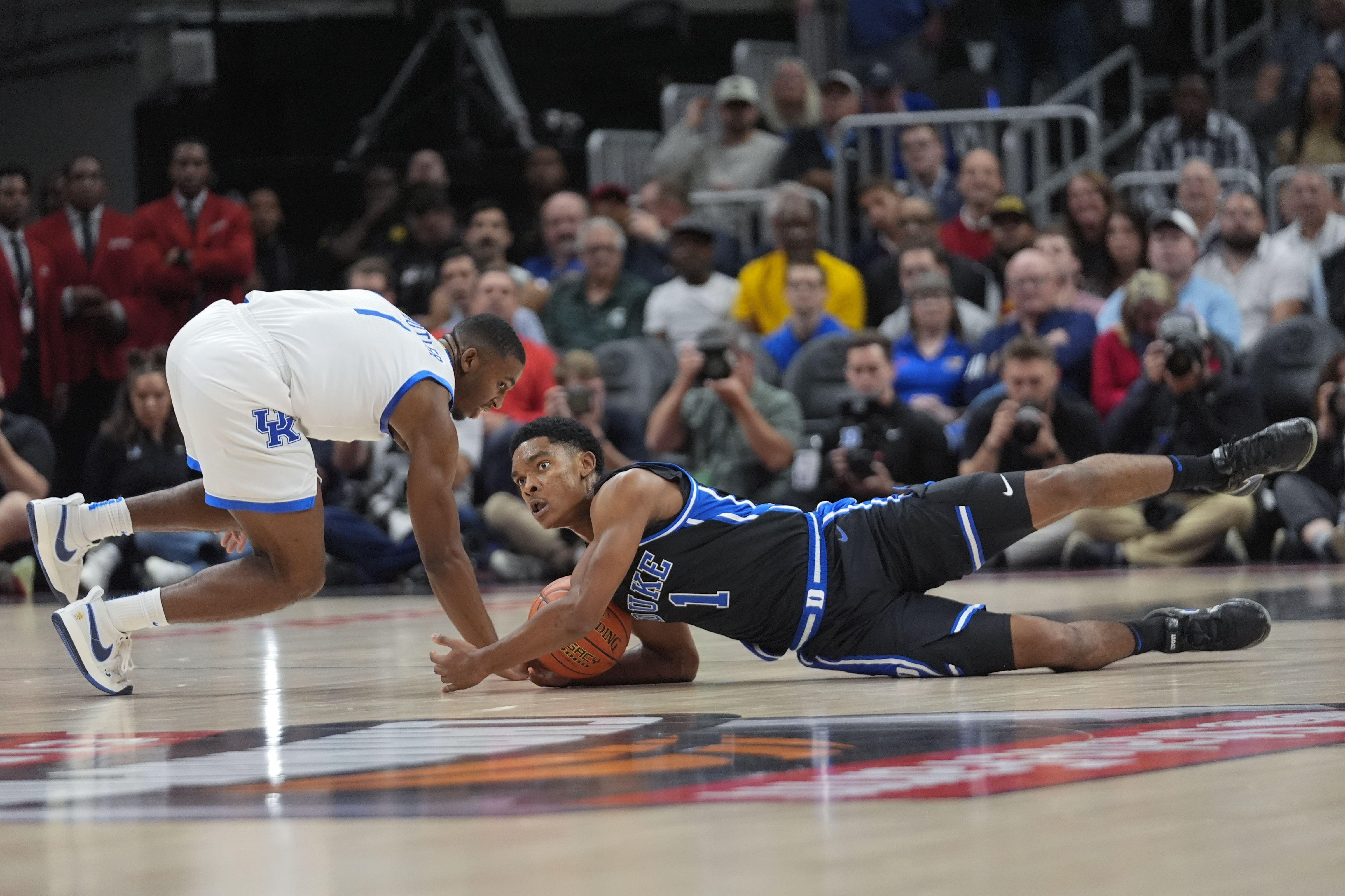 Duke guard Caleb Foster (1) and Kentucky guard Lamont Butler (1) dive for a loose ball during the first half of an NCAA college basketball game, Tuesday, Nov. 12, 2024, in Atlanta. (AP Photo/John Bazemore )