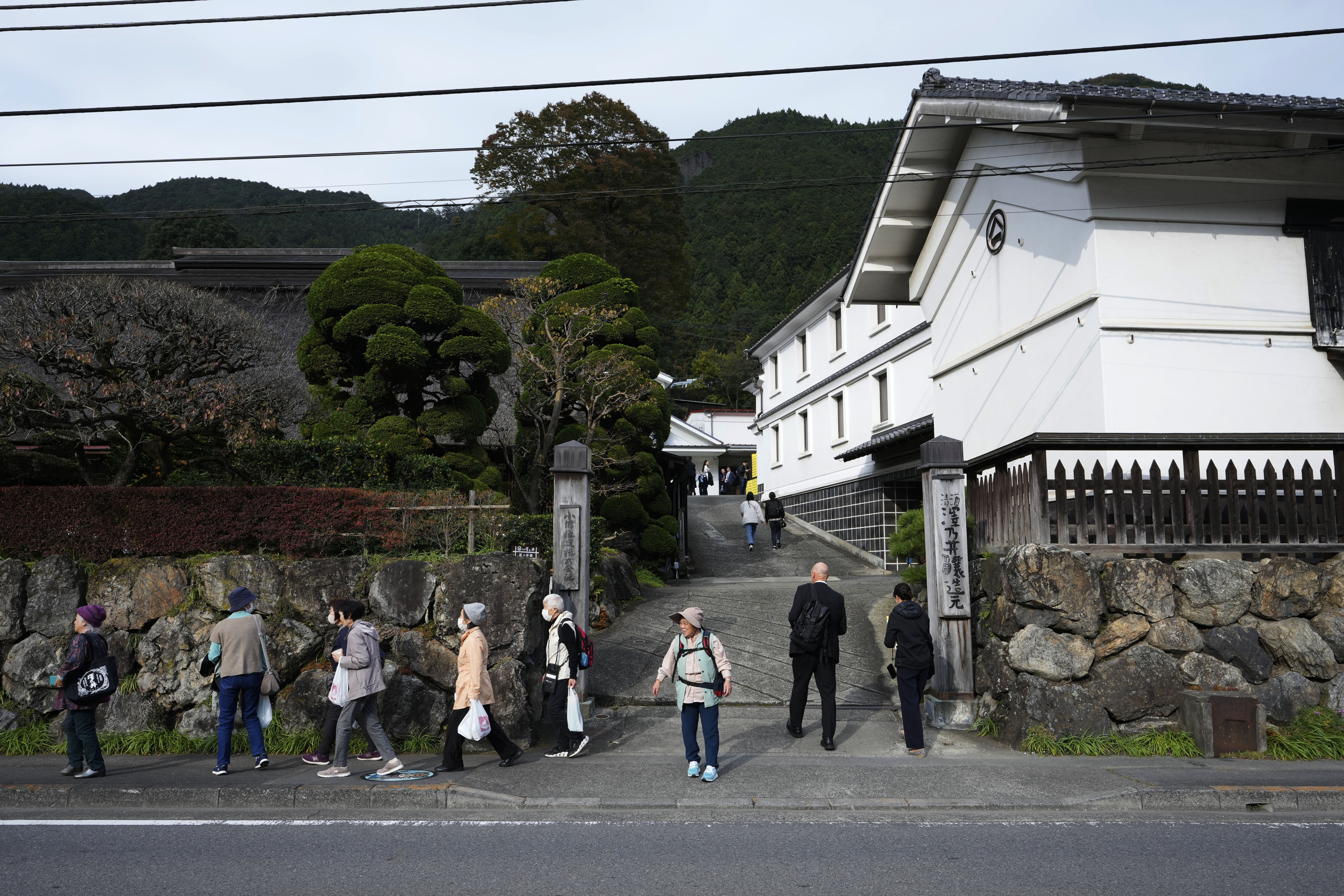 Visitors of Ozawa Sake Brewery leave as journalists enter the brewery on a media tour in Ome, on the western outskirts of Tokyo, Japan, Wednesday, Nov. 13, 2024. (AP Photo/Hiro Komae)