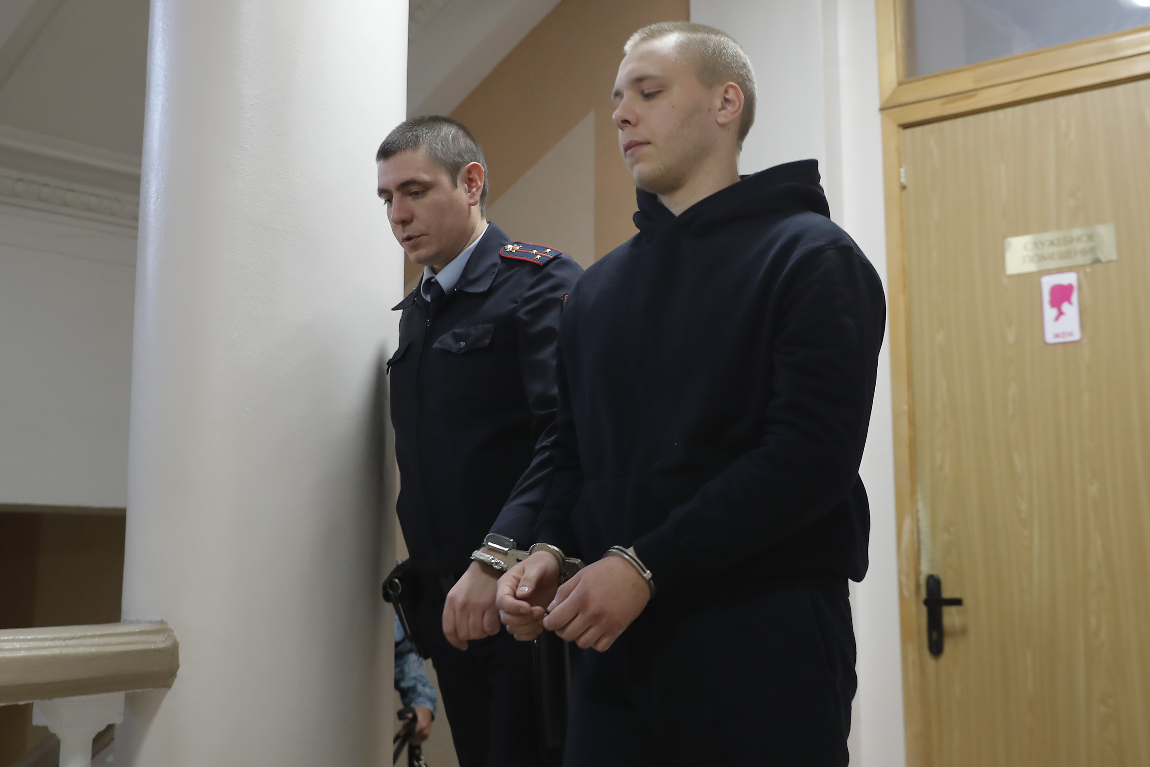 Nikita Zhuravel, right, is escorted by the police to a courtroom prior to a hearing of a treason case in Volgograd, Russia, Thursday, Nov. 14, 2024. (AP Photo)