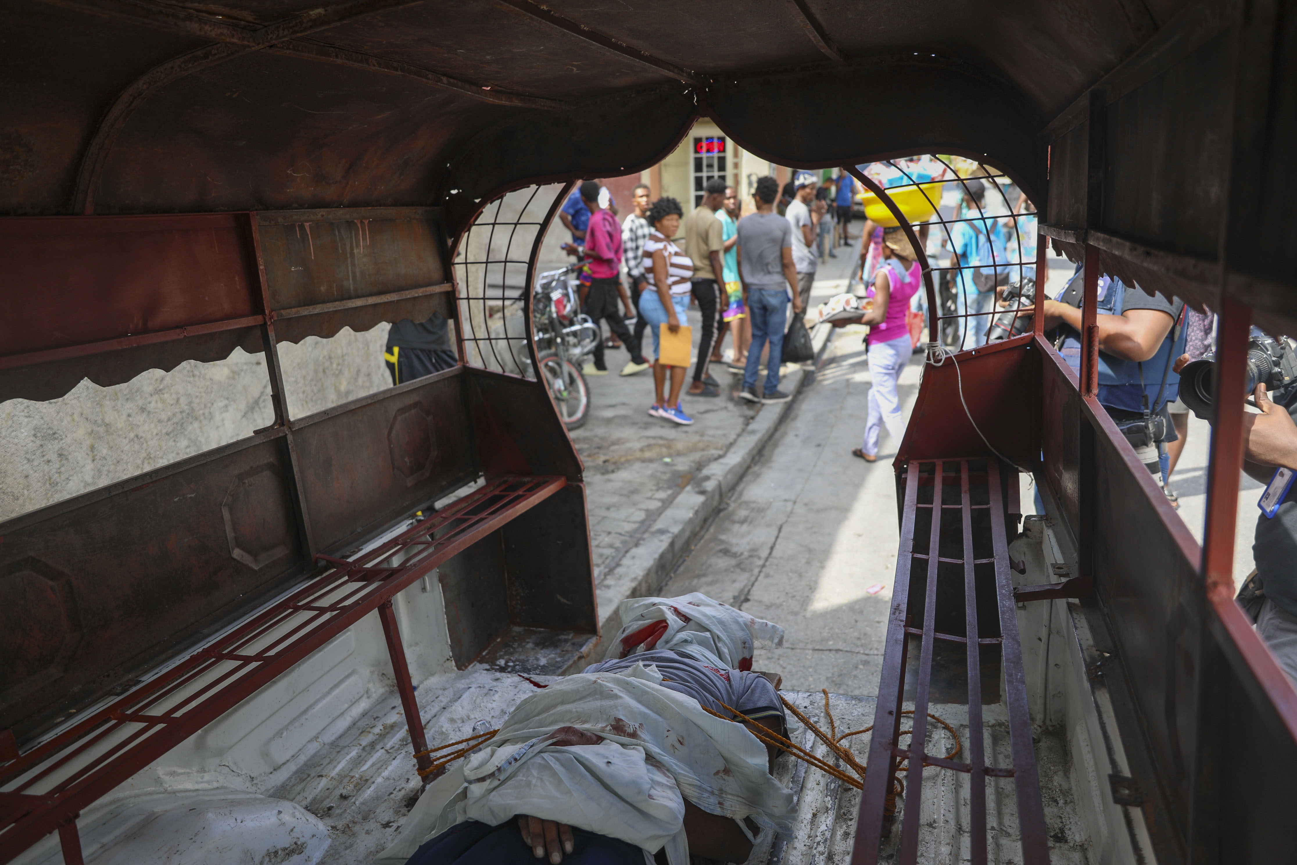 The body of a man who was shot dead by a stray bullet, is secured to the floor of a tap-tap, in the Solino neighborhood of Port-au-Prince, Haiti, Tuesday, Nov. 12, 2024. (AP Photo/Odelyn Joseph)