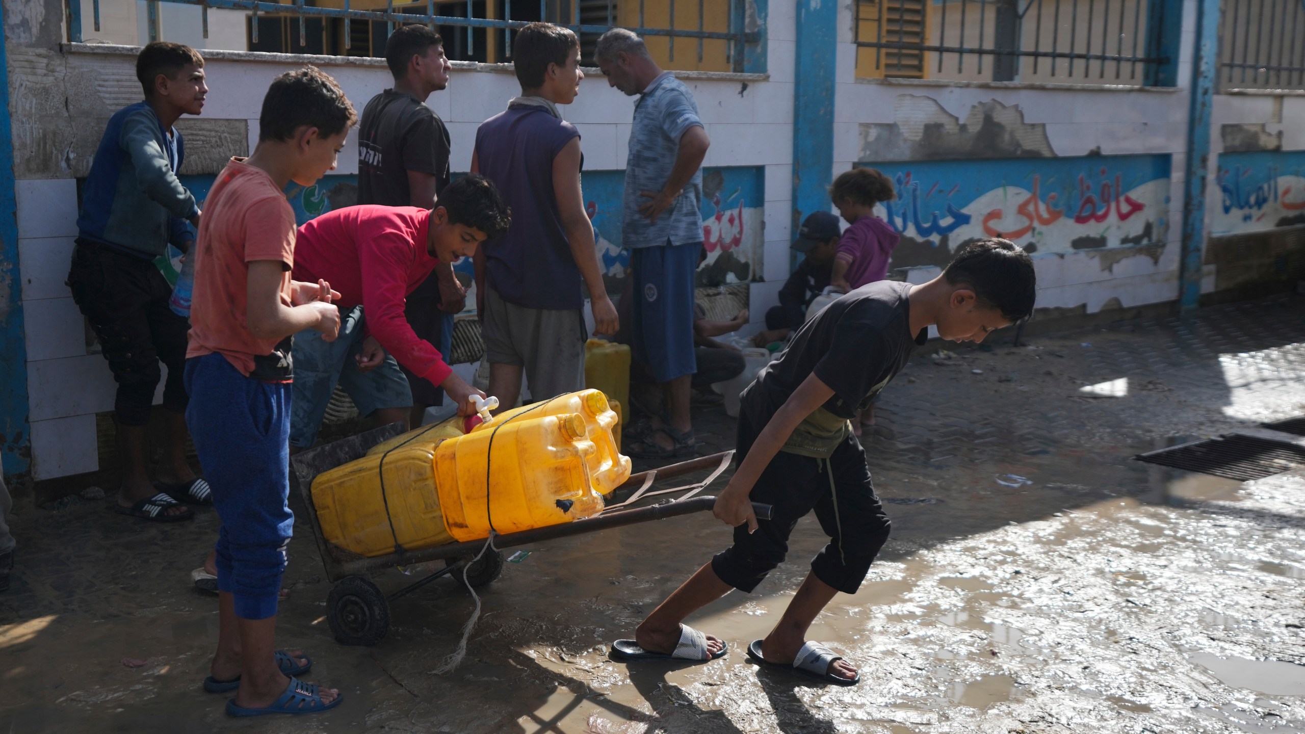 Palestinians collect clean drinking water at a desalination plant that now operates round the clock in Deir al-Balah, Gaza, a resource they barely had any access to during the war, Thursday, Nov. 14, 2024. (AP Photo/Abdel Kareem Hana)