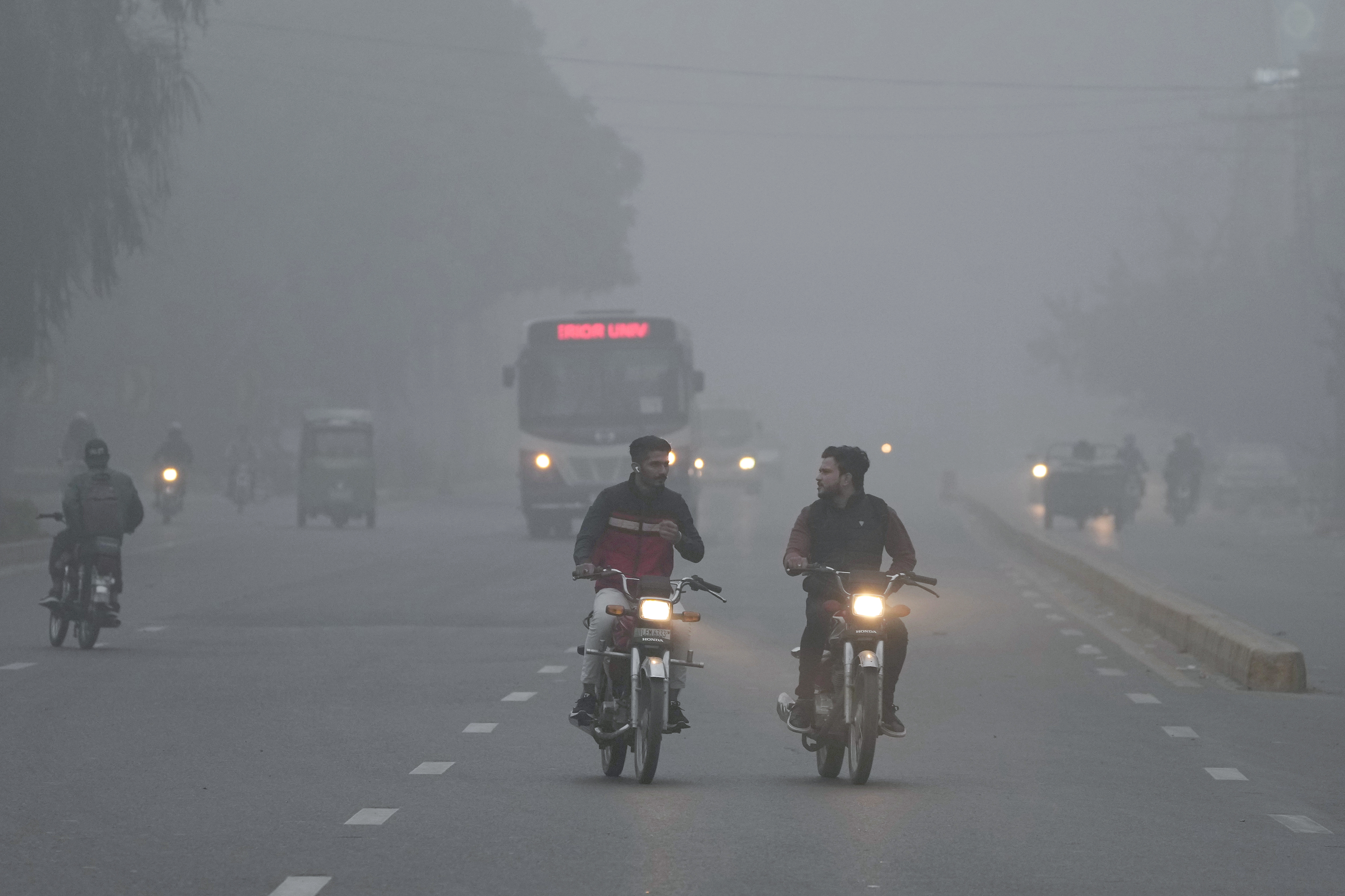 Vehicles and motorcyclists move with headlights on due to reduced visibility caused by smog enveloping the area of Lahore, Pakistan, Wednesday, Nov. 13, 2024. (AP Photo/K.M. Chaudary)