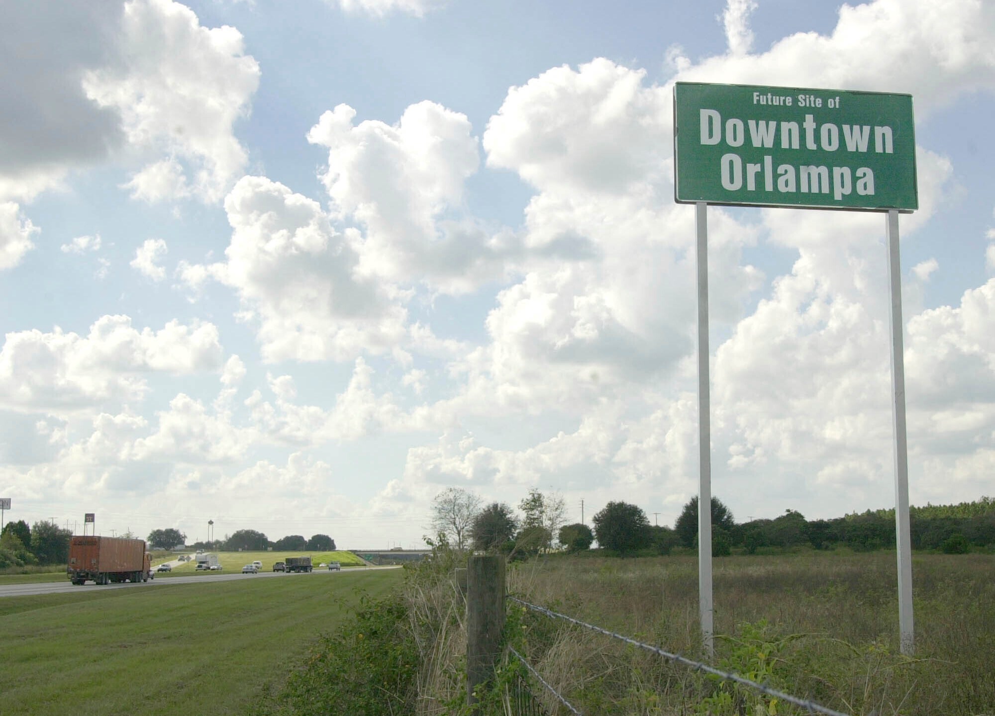 FILE - A tongue-in-cheek sign referencing what someday might be the heart of the sprawling metro areas of Orlando and Tampa is seen, installed by a private landowner, along Interstate 4 in Polk City, Fla., Oct. 24, 2002. (AP Photo/Peter Cosgrove, File)