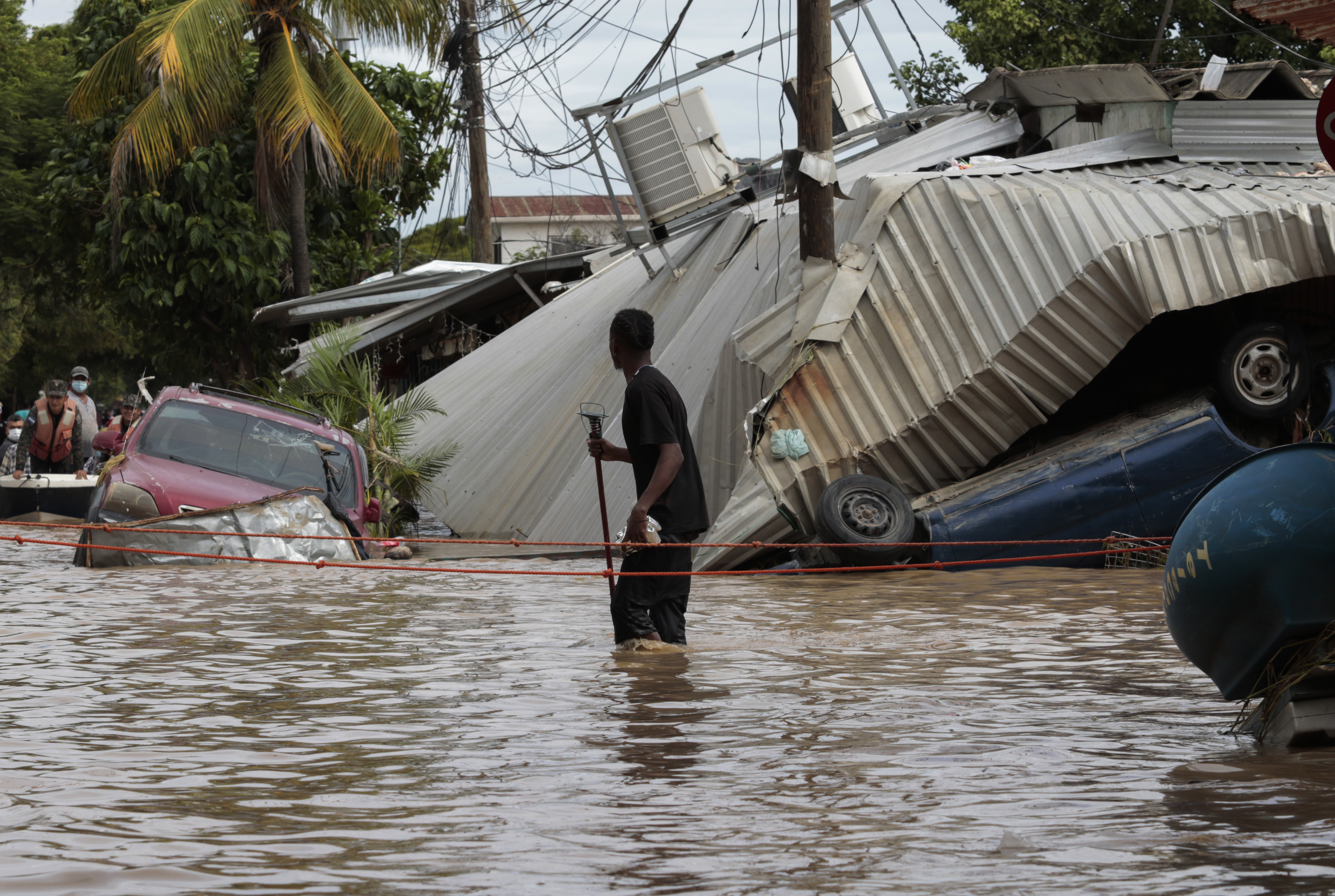 FILE - A resident walking through a flooded street looks back at storm damage caused by Hurricane Eta in Planeta, Honduras, Nov. 6, 2020. (AP Photo/Delmer Martinez, File)