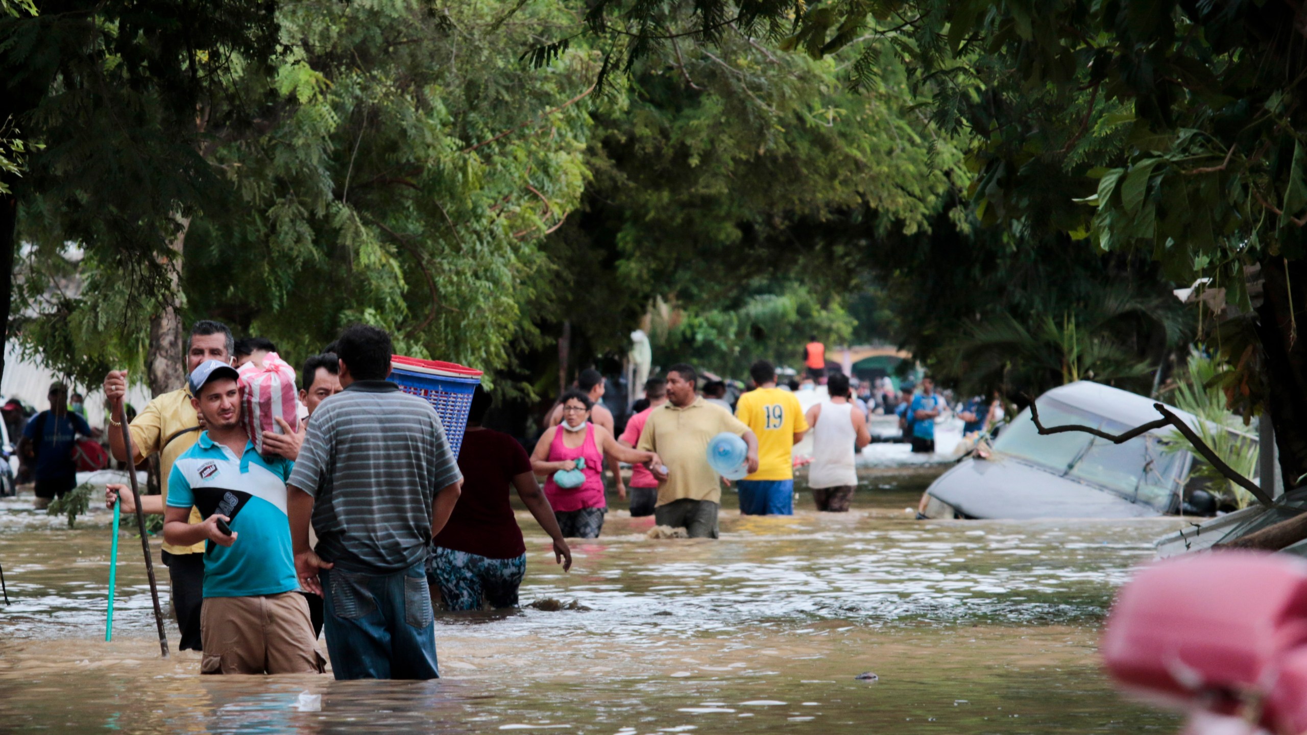 FILE - Residents walk past inundated vehicles in the flooded streets of Planeta, Honduras, Nov. 6, 2020, in the aftermath of Hurricane Eta. (AP Photo/Delmer Martinez, File)