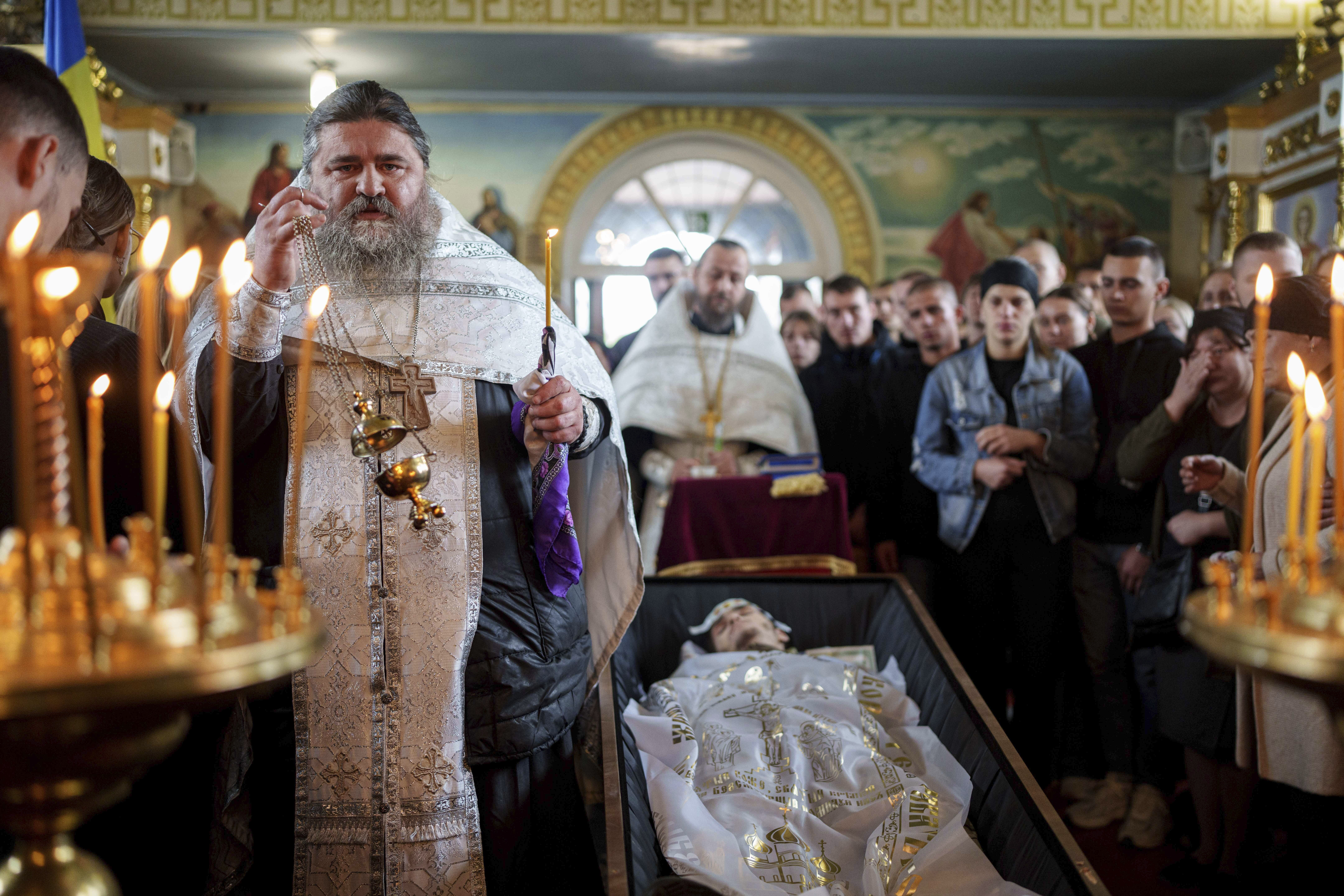 FILE - A priest reads a prayer for a fallen Ukrainian solfer fIhor Kusochek during the funeral ceremony in Bobrovytsia, Chernihiv region, Ukraine, on Oct. 4, 2024. (AP Photo/Evgeniy Maloletka, File)