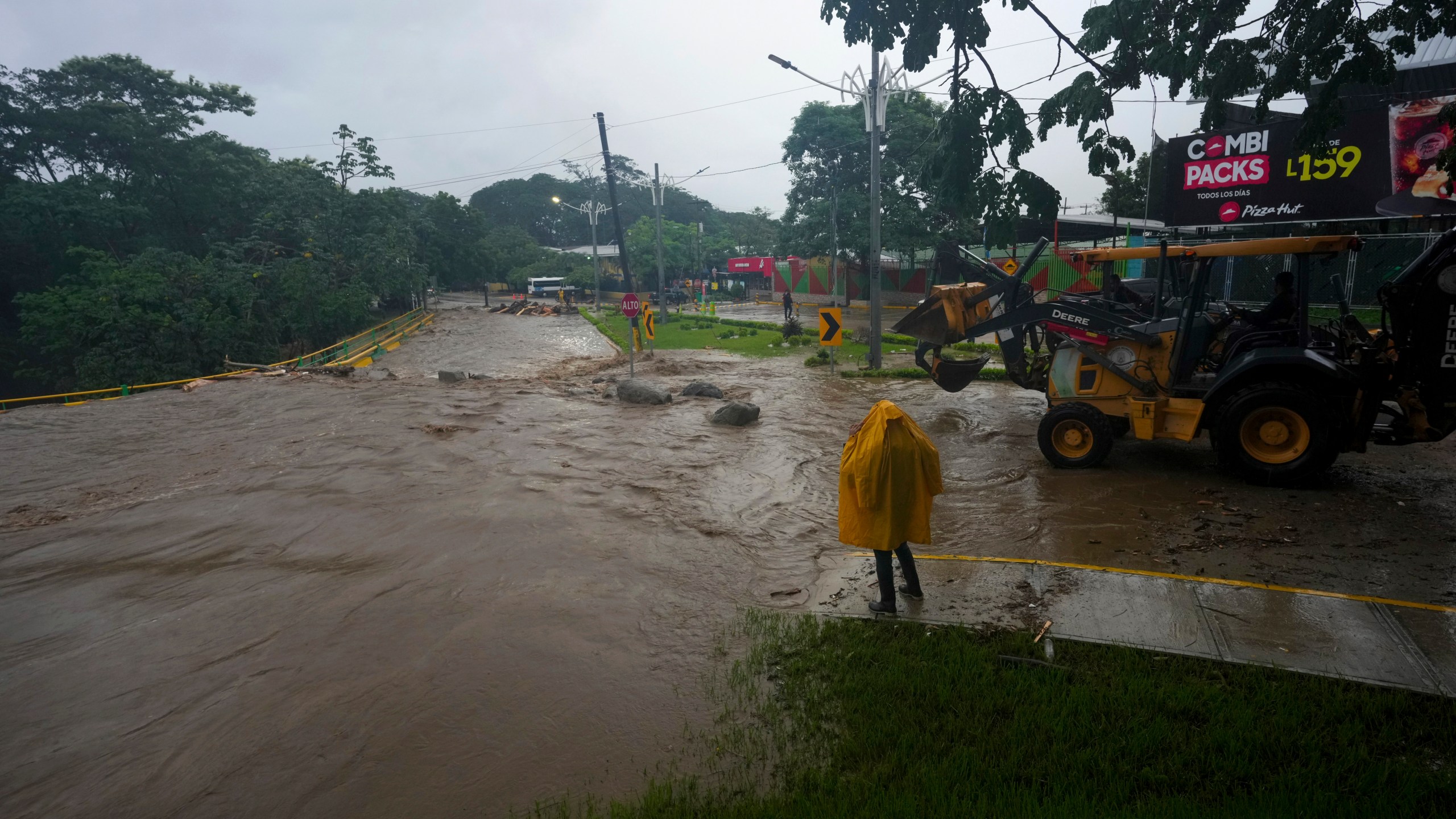 A worker stands alongside an overflowing river flooded by rains brought on by Tropical Storm Sara in San Pedro Sula, Honduras, Saturday, Nov. 16, 2024. (AP Photo/Moises Castillo)