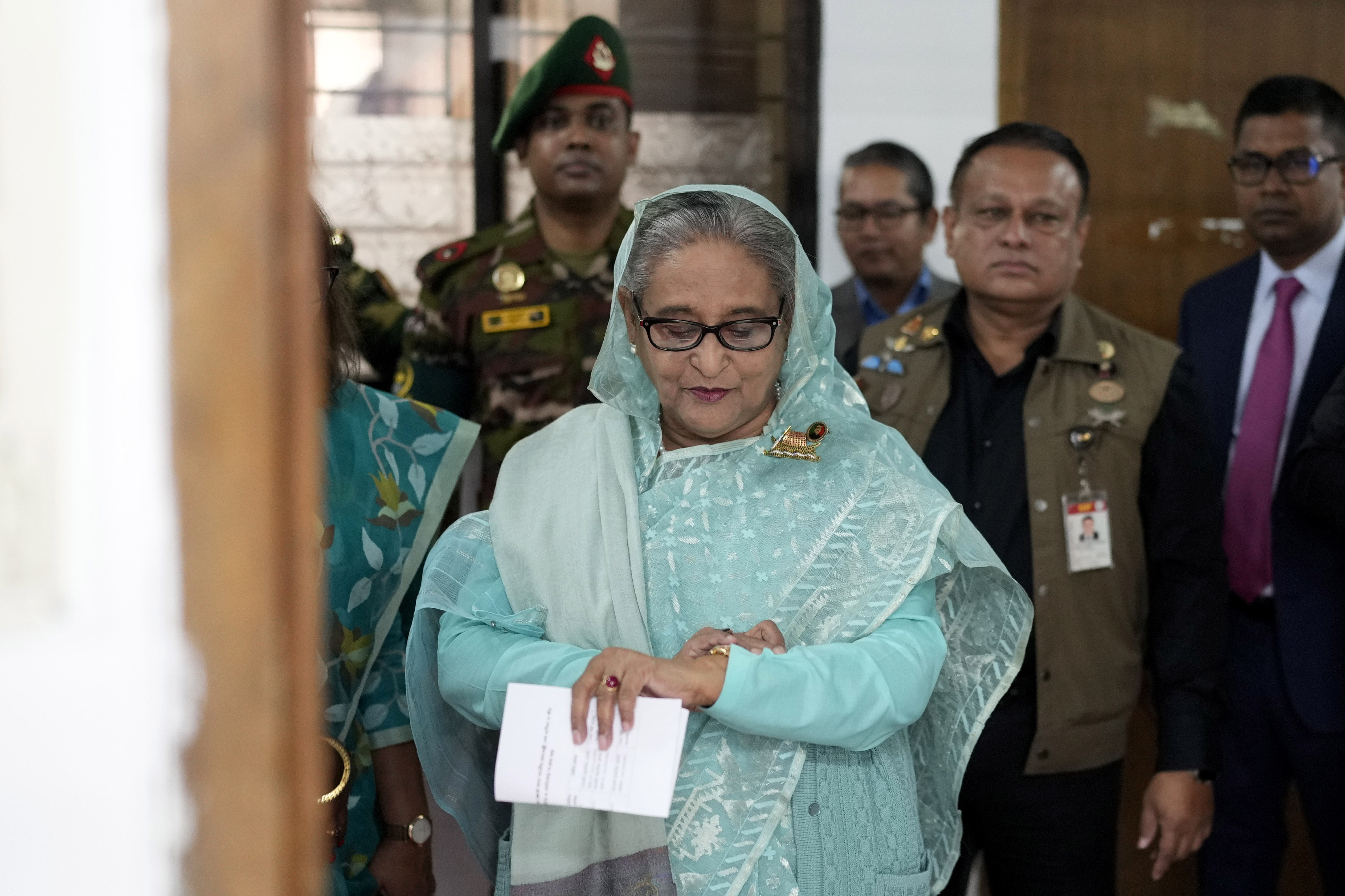 FILE- Bangladesh Prime Minister Sheikh Hasina checks her watch as she waits for the official opening time to cast her vote in Dhaka, Bangladesh, Jan. 7, 2024. (AP Photo/Altaf Qadri, File)