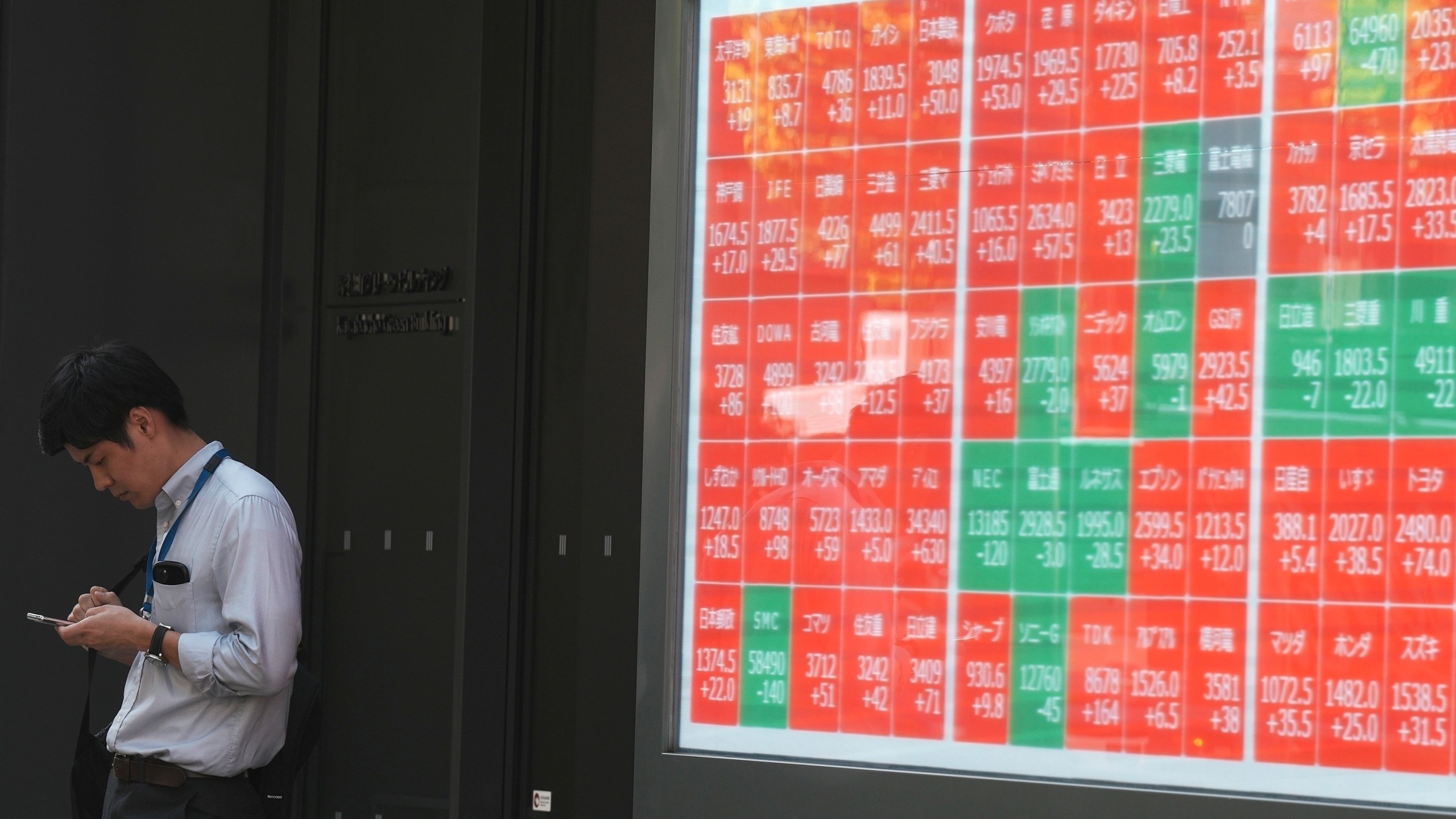 FILE - A person stands near an electronic stock board showing Japan's Nikkei index at a securities firm in Tokyo, on Sept. 18, 2024. (AP Photo/Eugene Hoshiko, File)