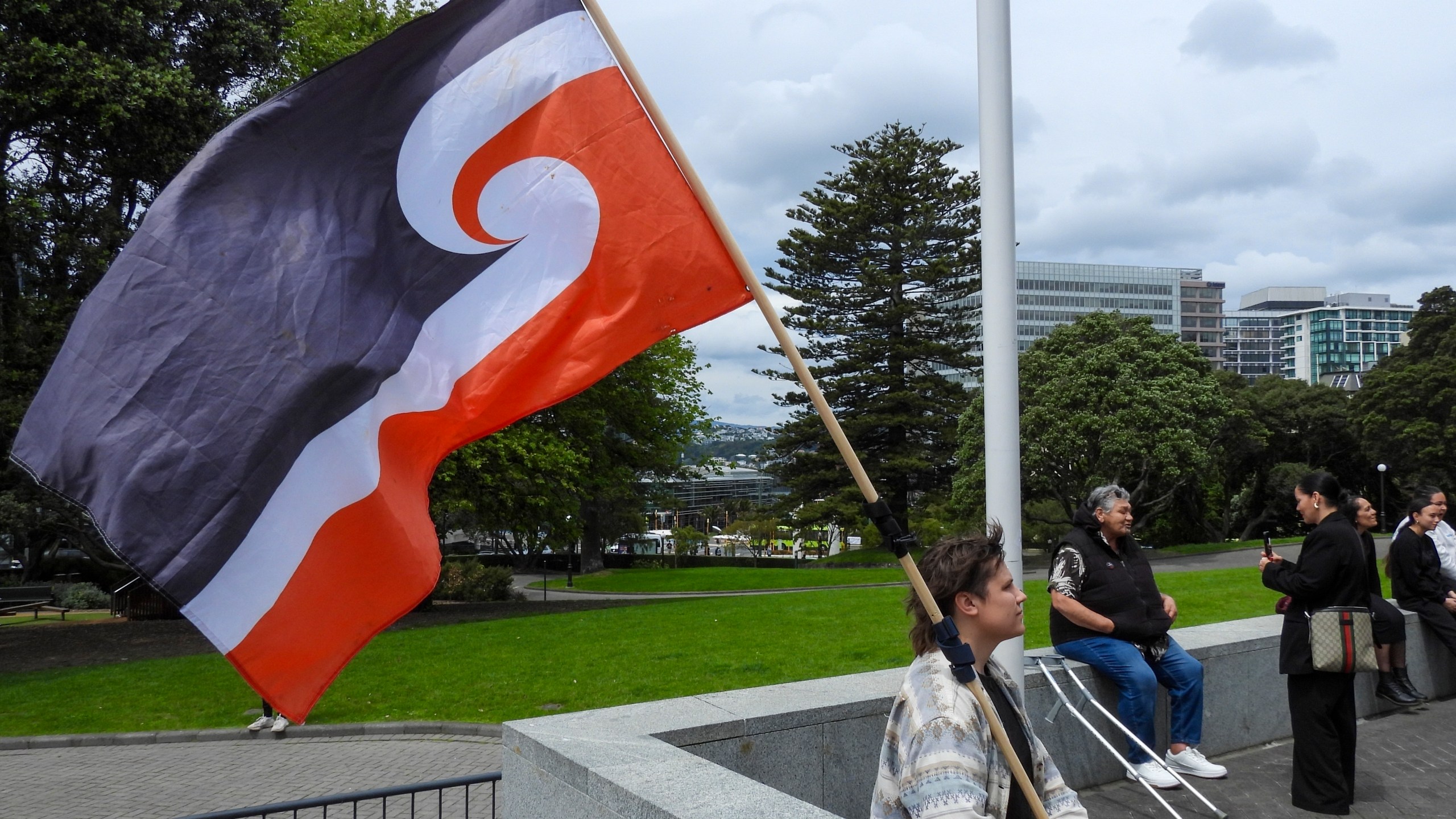 FILE - A protester against the Treaty Principles Bill sits outside Parliament in Wellington, New Zealand, Thursday, Nov. 14, 2024. (AP Photo/Charlotte Graham-McLay, File)