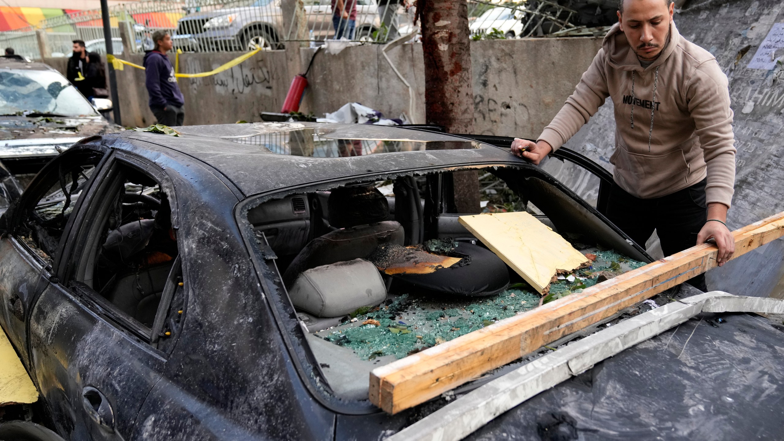 A man removes debris from his damaged car at the site where an Israeli airstrike on Sunday evening hit in central Beirut, Lebanon, Monday, Nov. 18, 2024. (AP Photo/Hussein Malla)