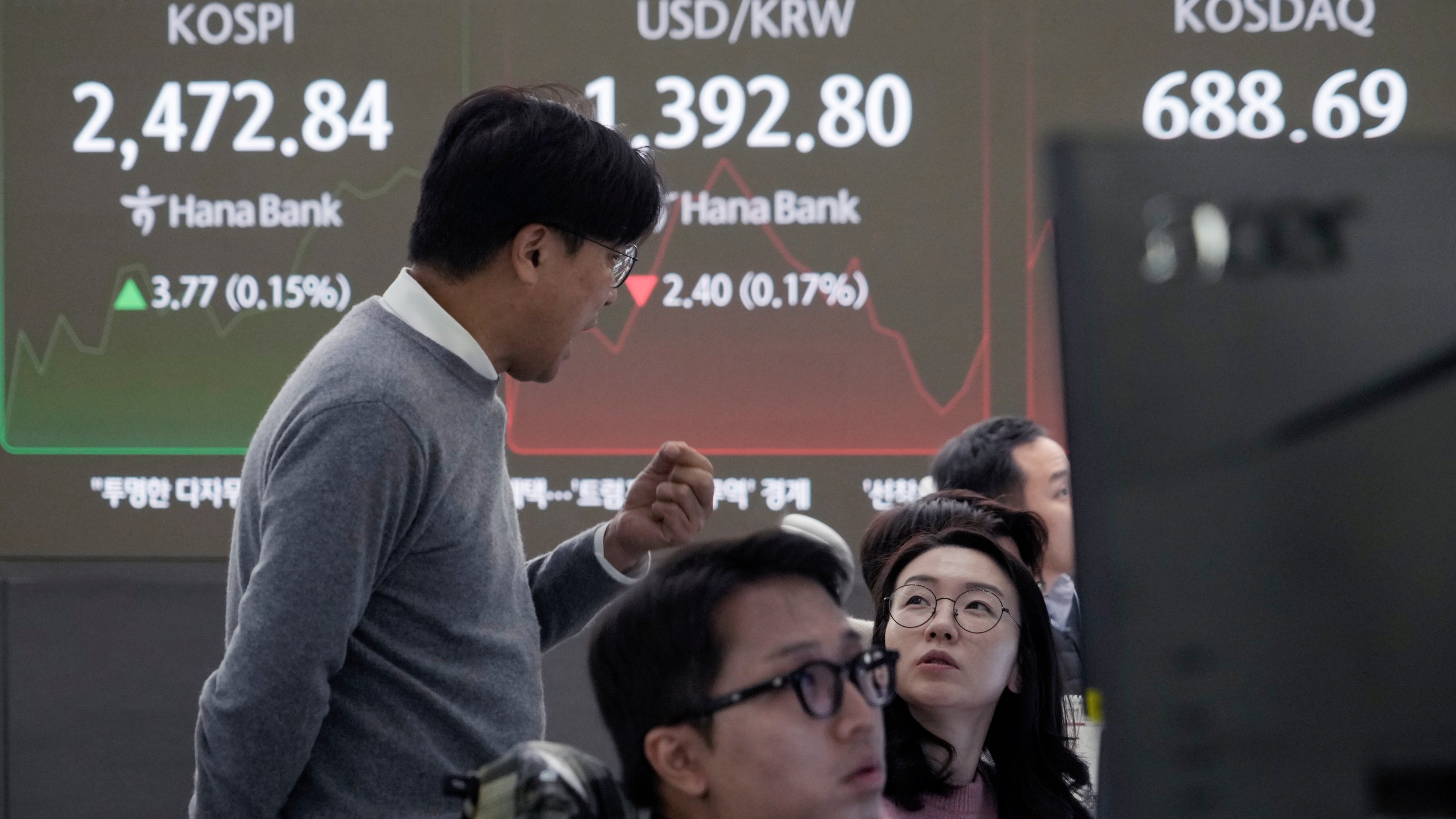 Currency traders work near a screen showing the Korea Composite Stock Price Index (KOSPI), left, and the foreign exchange rate between U.S. dollar and South Korean won, center, at the foreign exchange dealing room of the KEB Hana Bank headquarters in Seoul, South Korea, Tuesday, Nov. 19, 2024. (AP Photo/Ahn Young-joon)