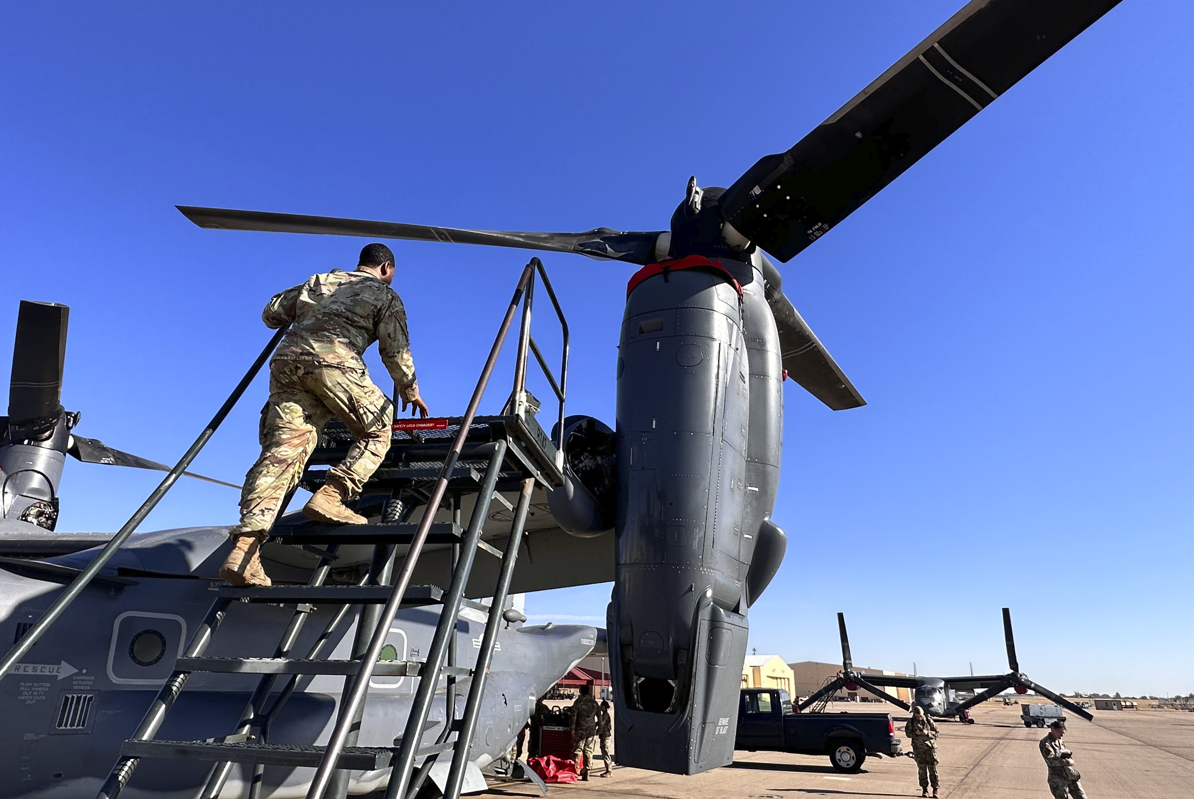 Master Sgt. Frank Williams, the production superintendent of the 20th Special Operations aircraft maintenance squadron at Cannon Air Force Base, N.M., climbs a ladder to show where hydraulic lines at the joint of the rotating engine and transmission need to be checked on the Osprey after flights, Oct. 8, 2024. (AP Photo/Tara Copp)