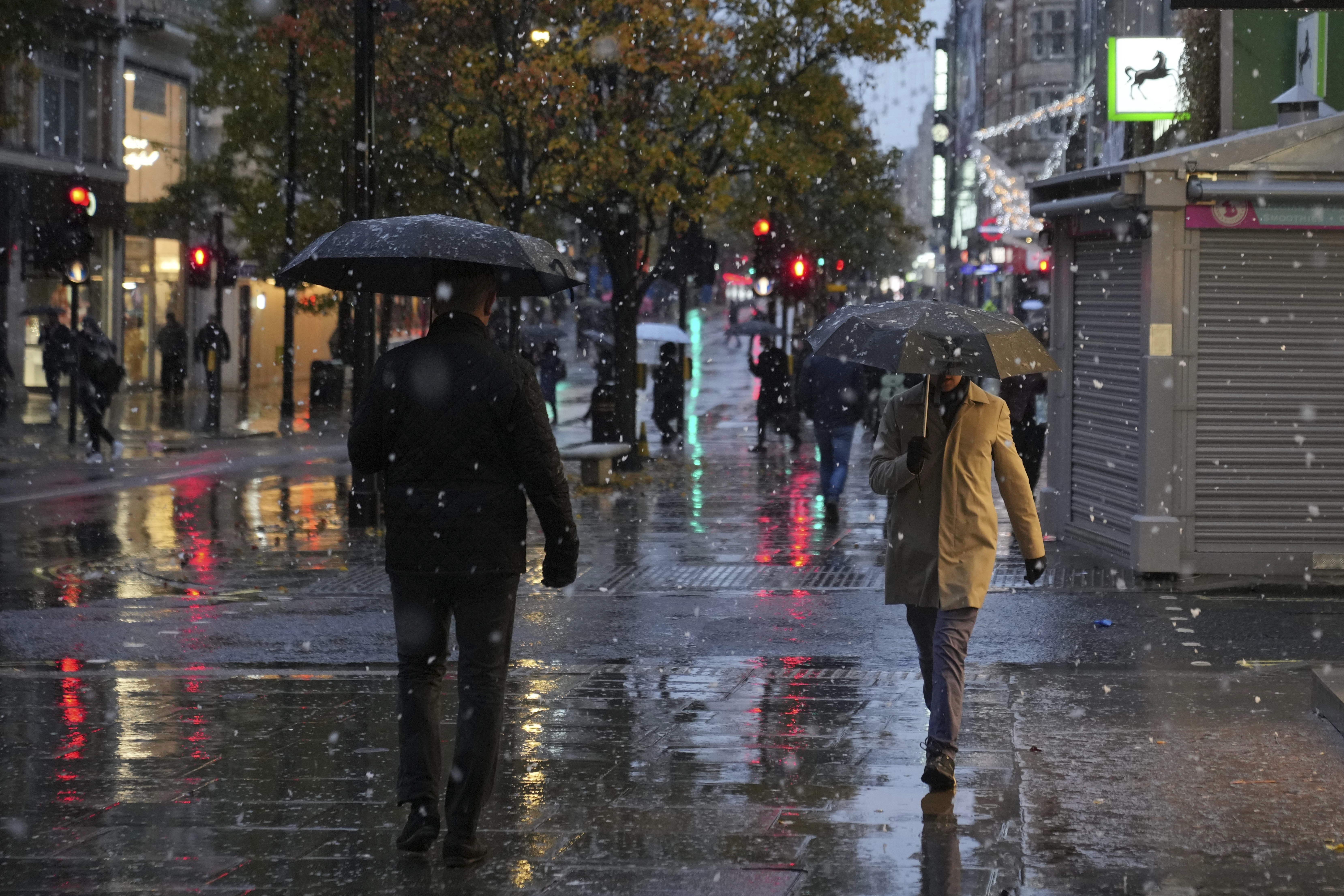 People walk along the Oxford Street as snow falls in London, Tuesday, Nov. 19, 2024. (AP Photo/Kin Cheung)