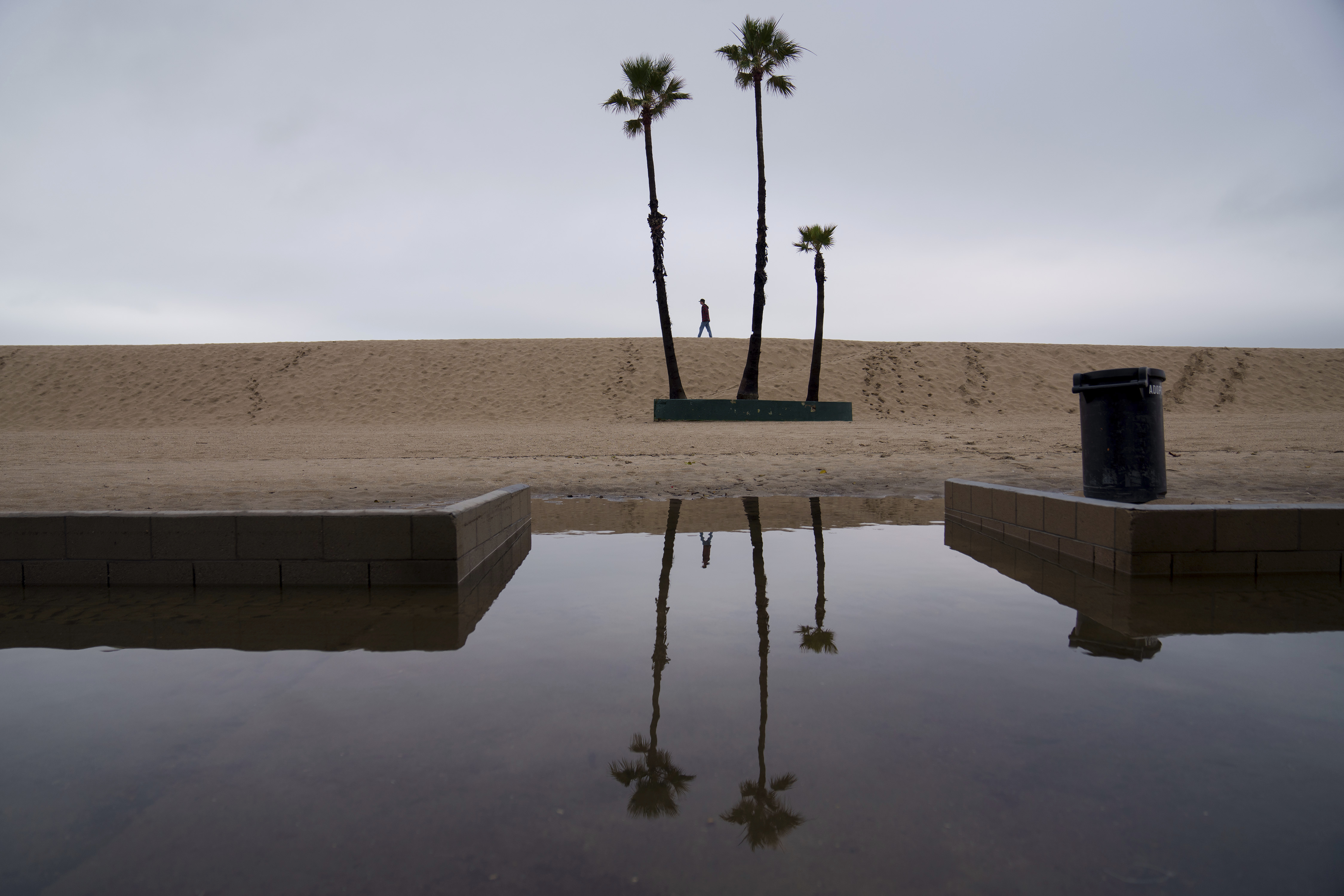 FILE - A person walks along the beach with flooding along the boardwalk Thursday, Feb. 1, 2024 in Seal Beach, Calif. (AP Photo/Eric Thayer, file)