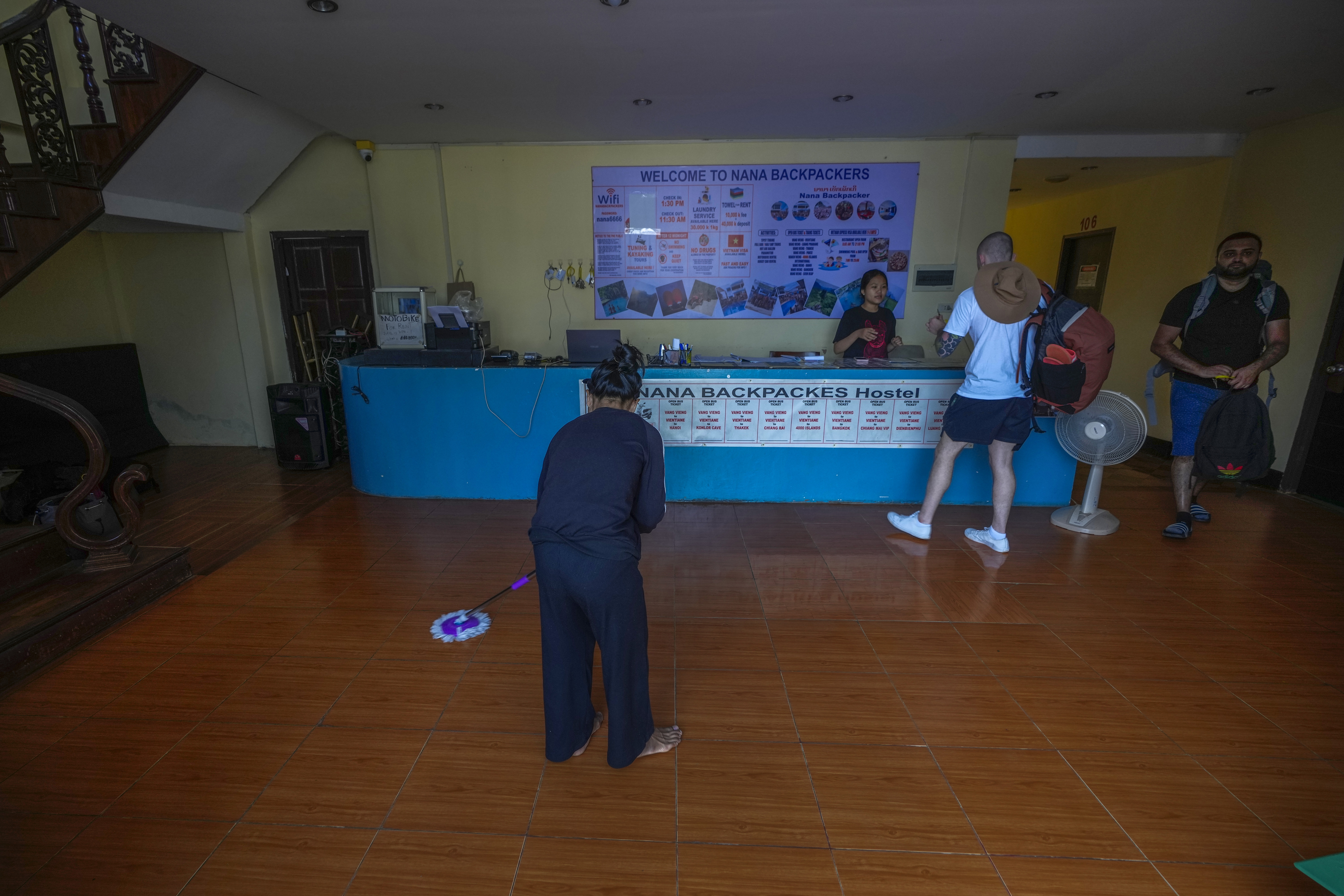 A woman swipes the floor as foreign tourists check out of Nana Backpack hostel in Vang Vieng, Laos, Tuesday, Nov. 19, 2024. (AP Photo/Anupam Nath)