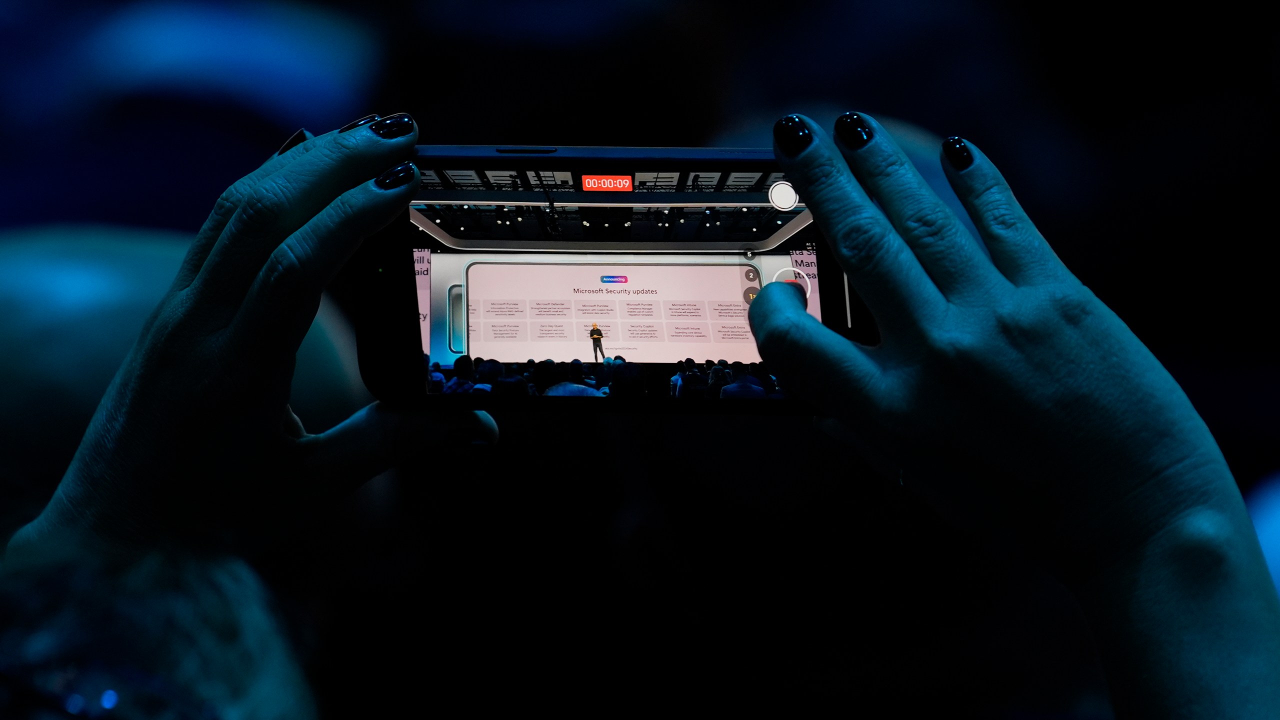 An attendee at the Microsoft Ignite conference records CEO Satya Nadella as he delivers the keynote address at the conference Tuesday, Nov. 19, 2024, in Chicago. (AP Photo/Charles Rex Arbogast)