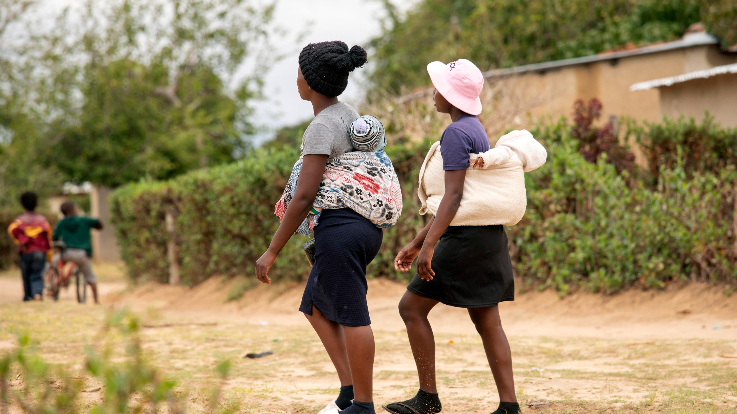 19 year old Sithulisiwe Moyo, right, and a friend, carry their babies on their backs at an outtreach clinic in Epworth, Zimbabwe, Thursday, Nov. 14, 2024. (AP Photo/Aaron Ufumeli)