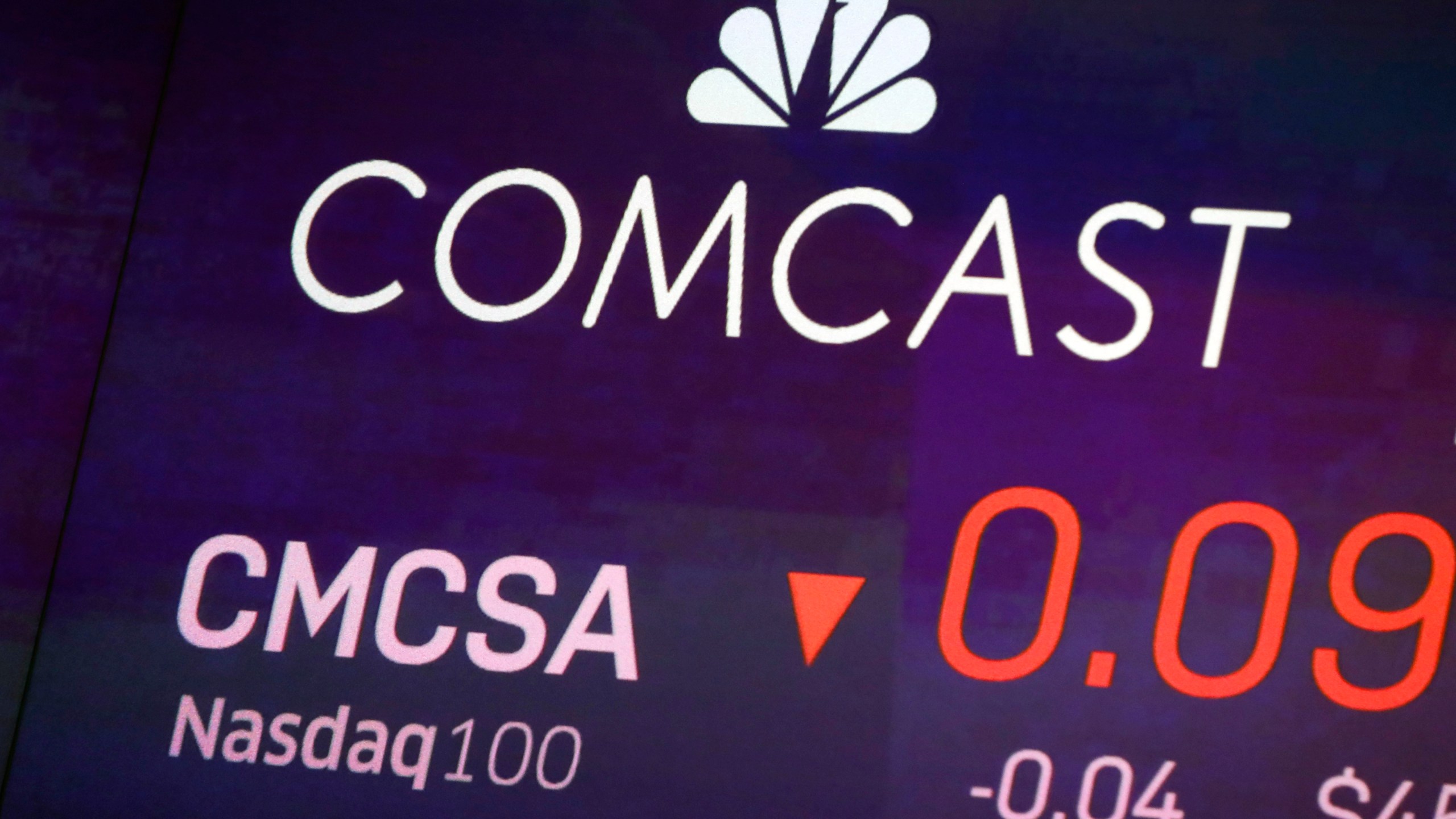 FILE - The symbol for Comcast appears on a screen at the Nasdaq MarketSite, on Oct. 1, 2019 in New York. (AP Photo/Richard Drew, File)