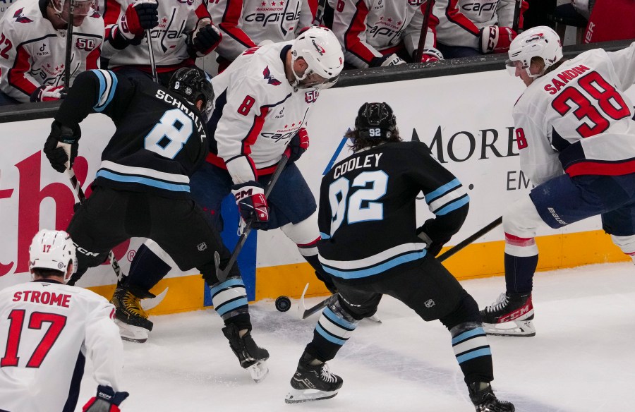 Utah Hockey Club centers Nick Schmaltz (8) and Logan Cooley (92) vie for the puck with Washington Capitals left wing Alex Ovechkin (8) as Capitals defenseman Rasmus Sandin (38) and center Dylan Strome (17) look on during the first period of an NHL hockey game Monday, Nov. 18, 2024, in Salt Lake City. (AP Photo/Bethany Baker)