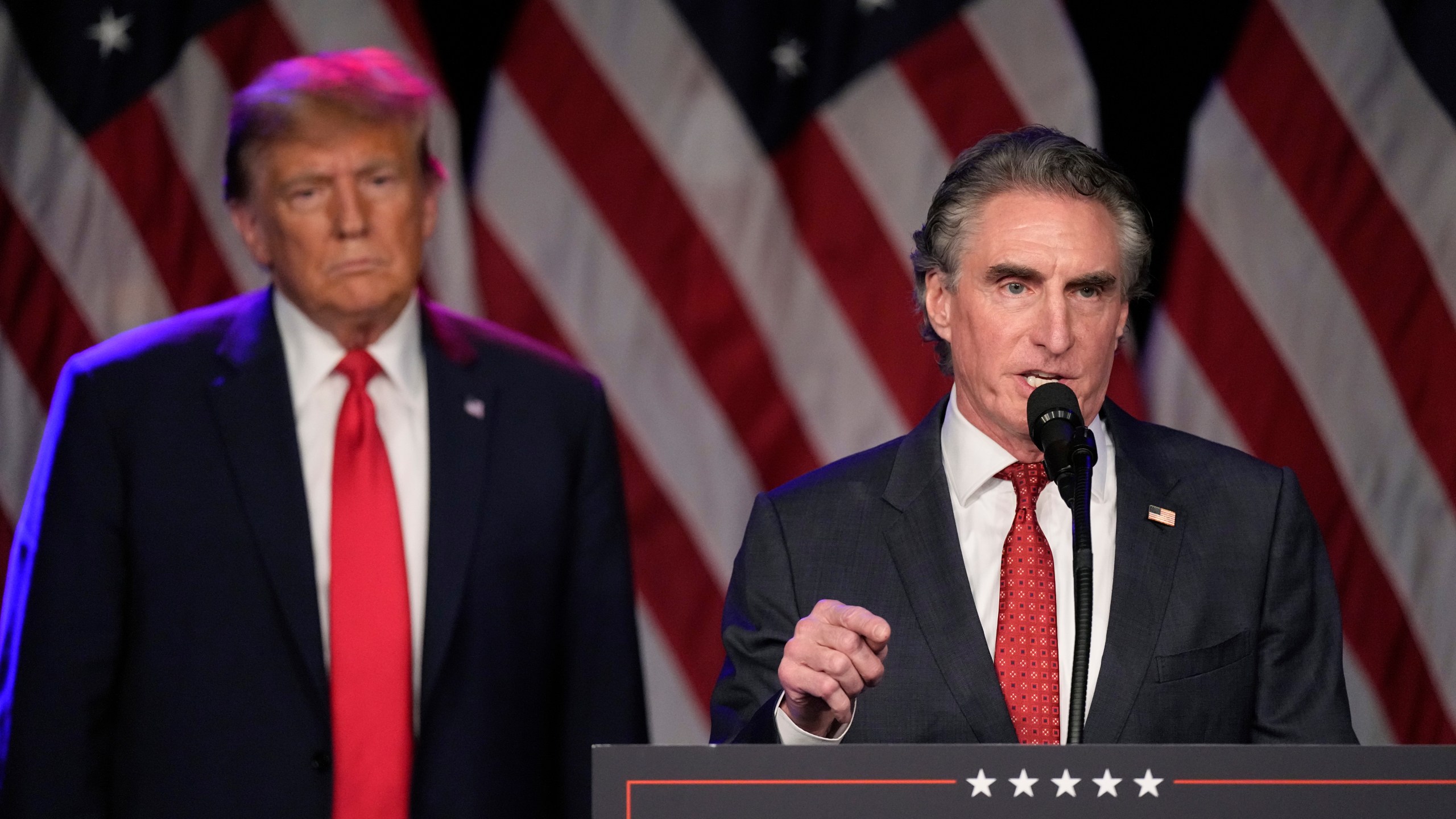 FILE - Republican presidential candidate former President Donald Trump listens as North Dakota Gov. Doug Burgum speaks at a caucus night rally in Las Vegas, Feb. 8, 2024. (AP Photo/Mark J. Terrill, File)