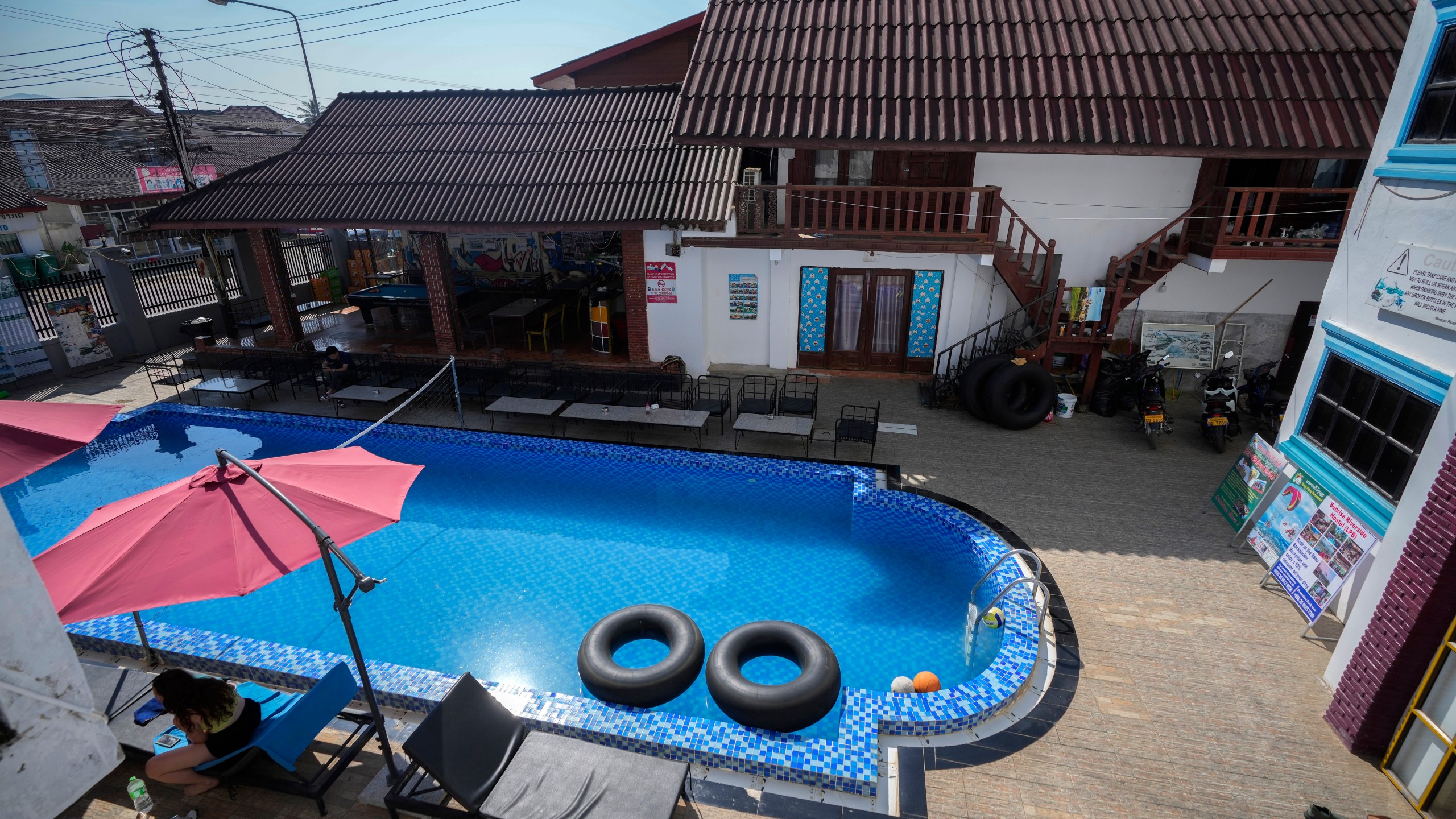 A foreign tourist rests near a swimming pool at Nana Backpackers hostel in Vang Vieng, Laos, Friday, Nov. 22, 2024. (AP Photo/Anupam Nath)