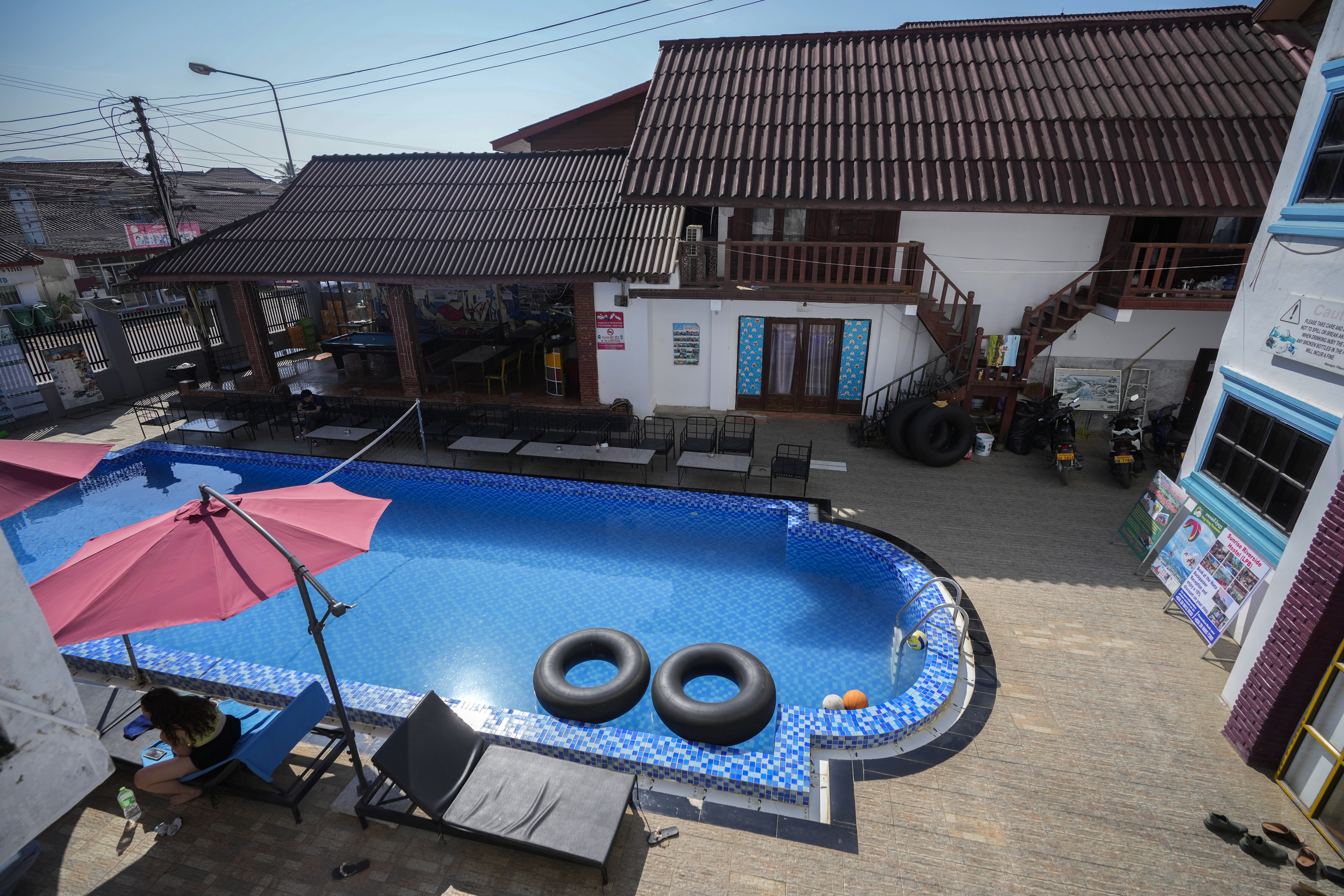 A foreign tourist rests near a swimming pool at Nana Backpackers hostel in Vang Vieng, Laos, Friday, Nov. 22, 2024. (AP Photo/Anupam Nath)