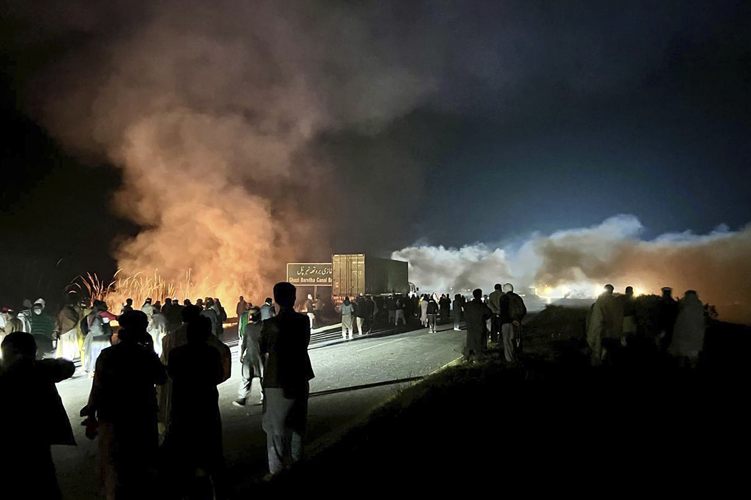 Supporters of imprisoned former premier Imran Khan's Pakistan Tehreek-e-Insaf party, burn bushes to reduce the impact of tear gas shells fired by police officers to disperse them during a rally demanding Khan's release, at a motorway in Ghazi in Attock district, Pakistan, Sunday, Nov. 24, 2024. (AP Photo/Maaz Awan)