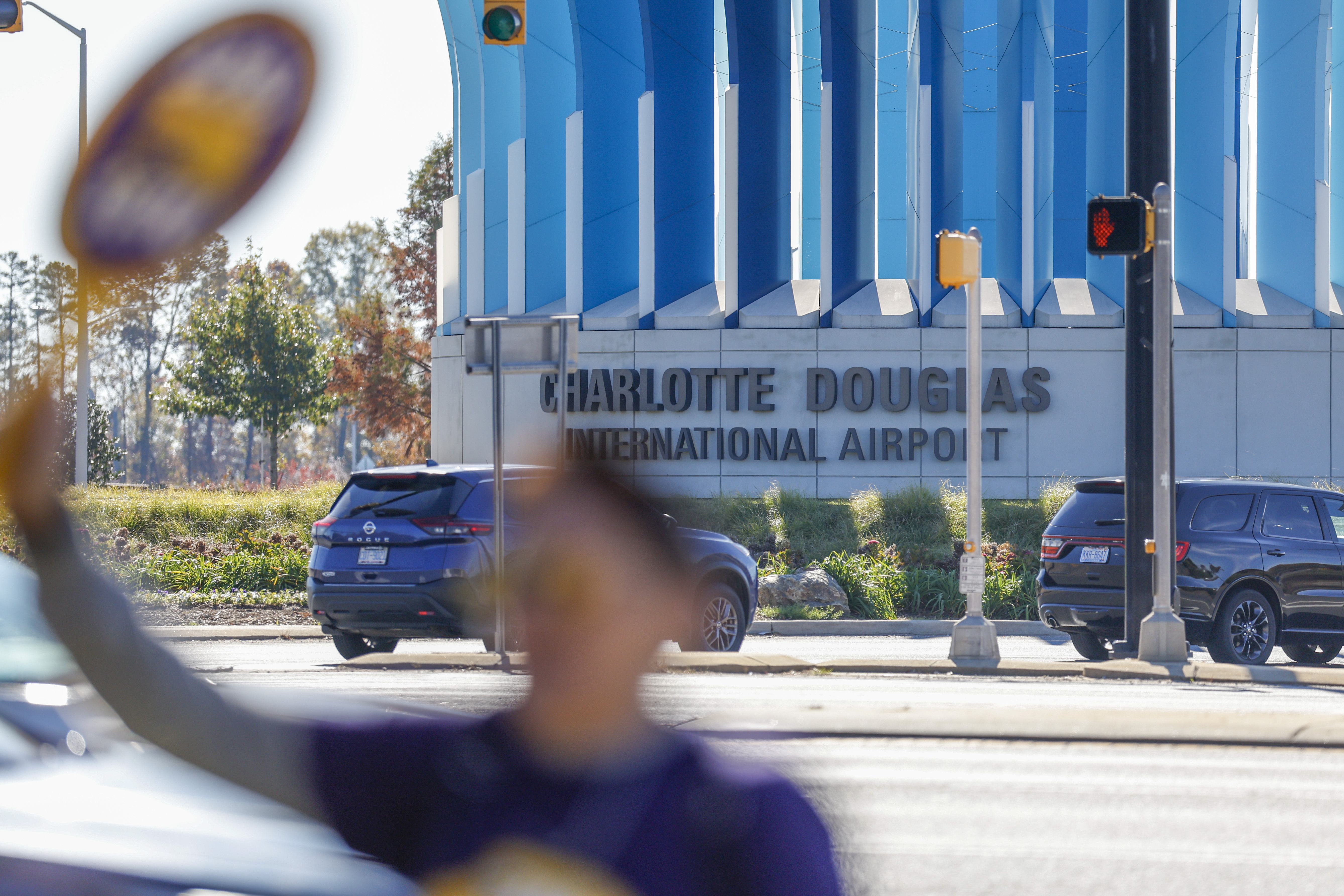 Airport workers wave signs as they march in front of the Charlotte Douglas International Airport in Charlotte, N.C., Monday, Nov. 25, 2024. (AP Photo/Nell Redmond)