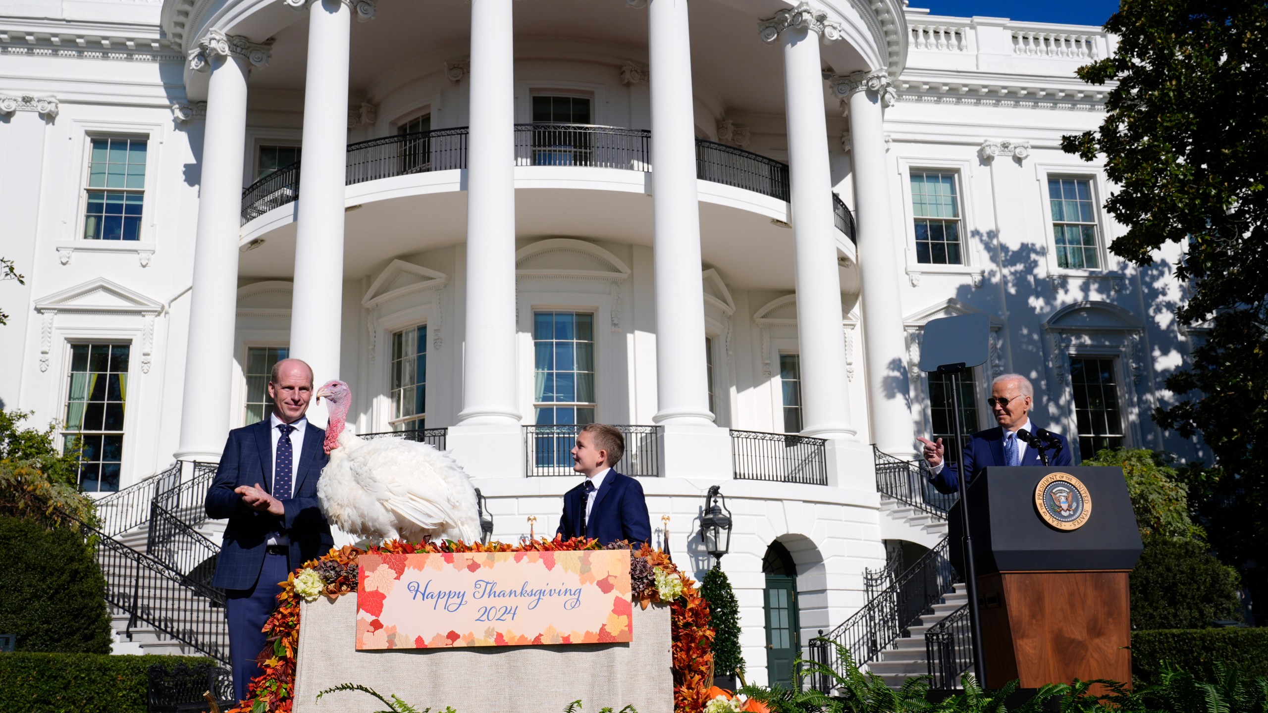 President Joe Biden speaks and pardons the national Thanksgiving turkey, Peach, during a pardoning ceremony on the South Lawn of the White House in Washington, Monday, Nov. 25, 2024, as John Zimmerman, chair of the National Turkey Federation and his son Grant, look on. (AP Photo/Susan Walsh)