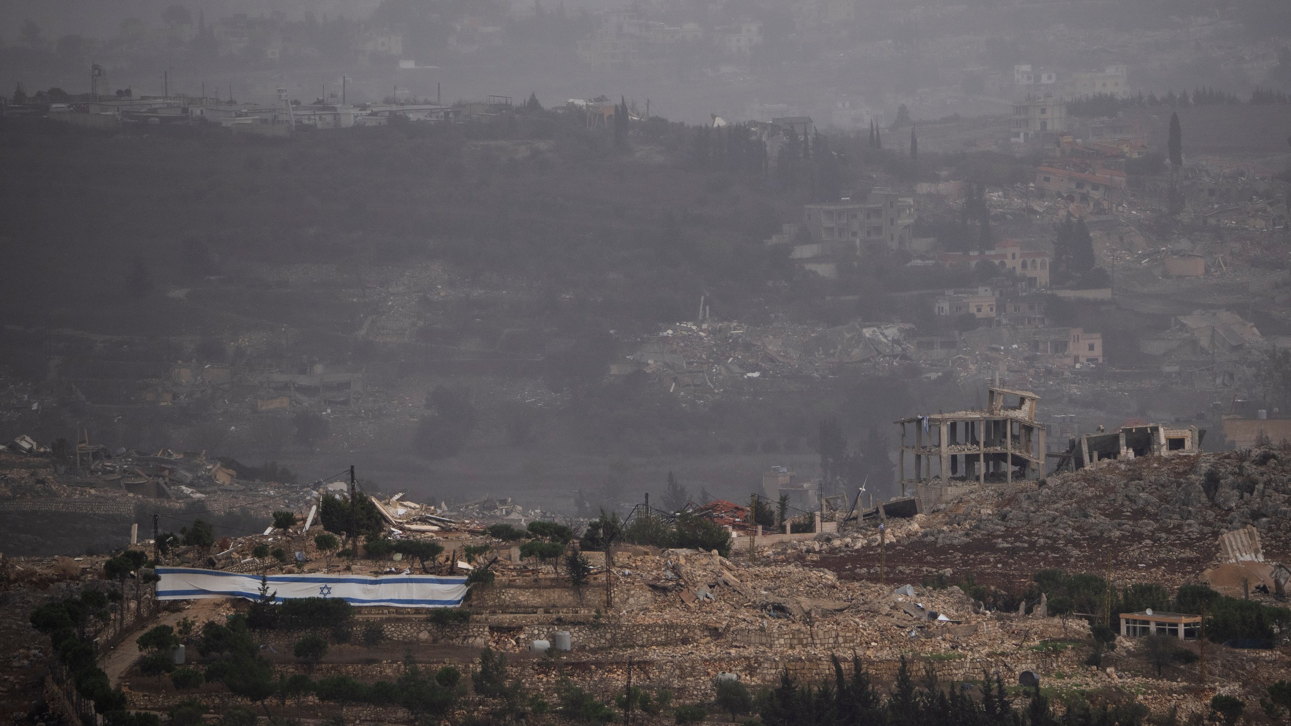 An Israeli flag stands next to destroyed buildings on an area in southern Lebanon as seen from northern Israel, Monday, Nov. 25, 2024. (AP Photo/Leo Correa)